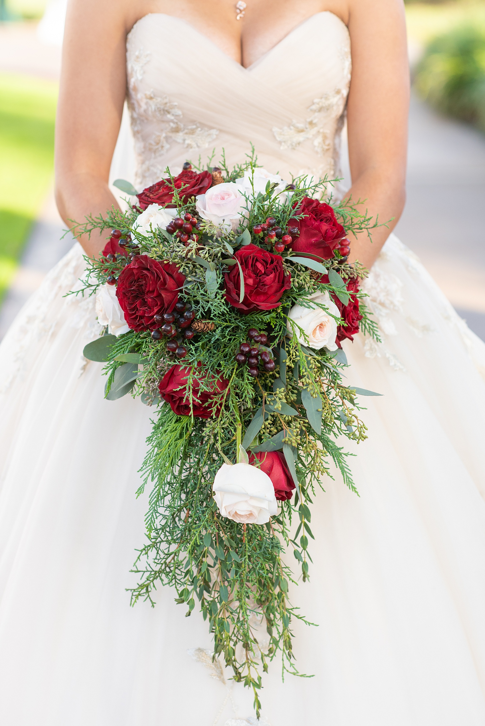 Walt Disney World photographs by Mikkel Paige Photography. The bride had a December themed wedding at the Grand Floridian Resort, Wedding Pavilion and Contemporary Hotel. It had a Beauty and the Beast theme and she wore a beautiful embroidered dress, befitting of a princess. Her pink and red rose bouquet had holiday greenery, a Swarovski crystal hidden mickey and small pine cones in it with a cascading effect. #disneywedding #disneybride #waltdisneyworld #DisneyWorldWedding #cascadingbouquet