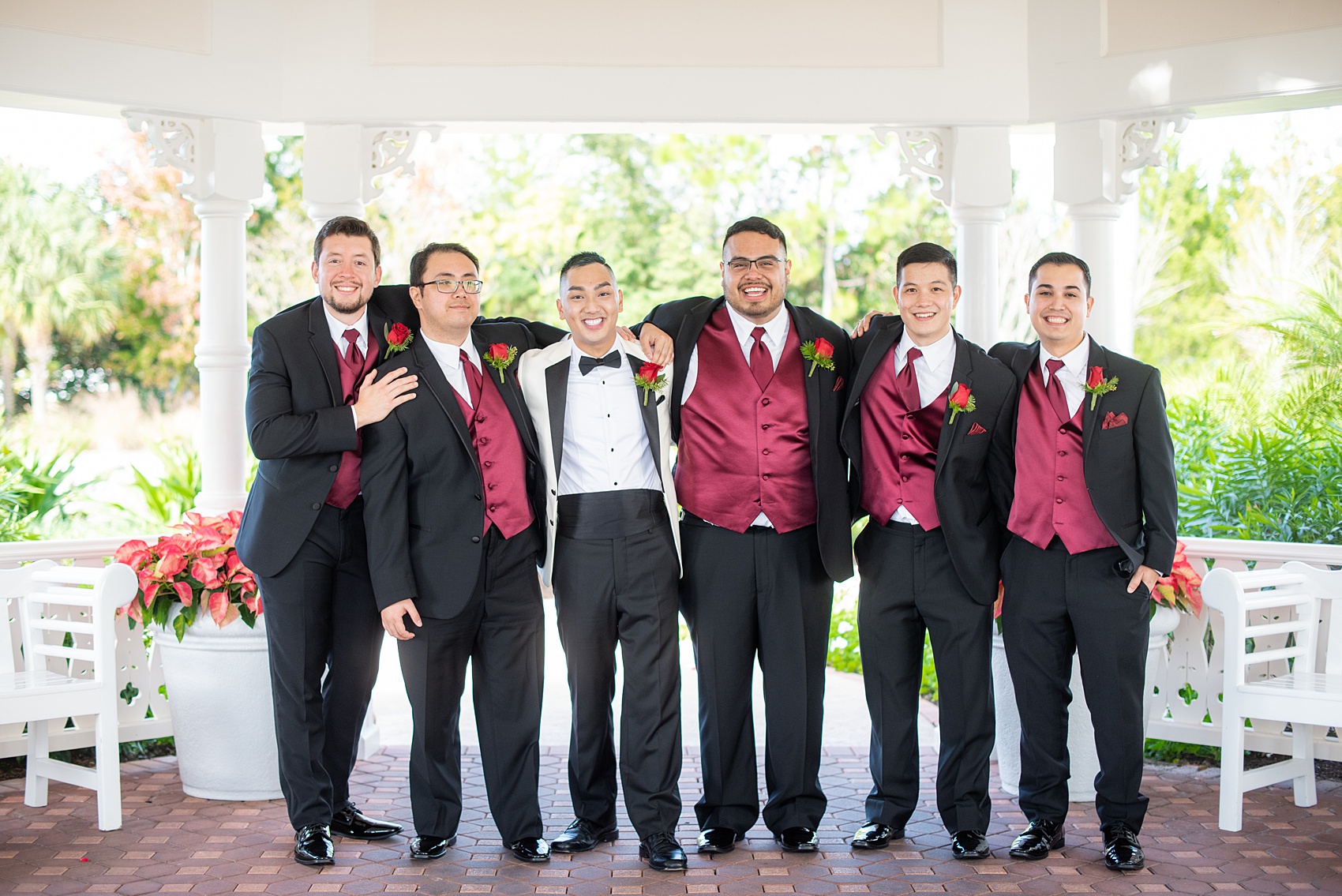 Photographs of a Walt Disney World bridal party by Mikkel Paige Photography. The groom wore a white tuxedo to his wedding venues of the Grand Floridian, Wedding Pavilion and The Contemporary Resort. They all wore rose boutonnieres and marvel comic cufflinks, a small detail that was an awesome way to incorporate a fun idea. #disneywedding #disneybride #waltdisneyworld #DisneyWorldWedding #BeautyandtheBeast #redrosewedding