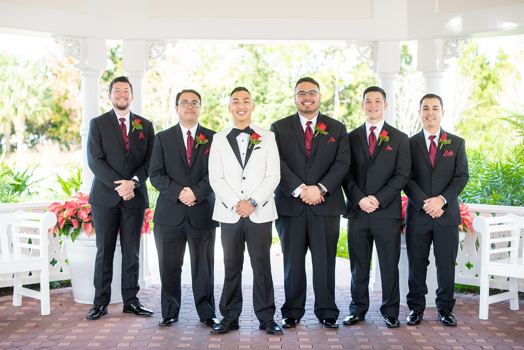 Photographs of a Walt Disney World bridal party by Mikkel Paige Photography. The groom wore a white tuxedo to his wedding venues of the Grand Floridian, Wedding Pavilion and The Contemporary Resort. They all wore rose boutonnieres and marvel comic cufflinks, a small detail that was an awesome way to incorporate a fun idea. #disneywedding #disneybride #waltdisneyworld #DisneyWorldWedding #BeautyandtheBeast #redrosewedding