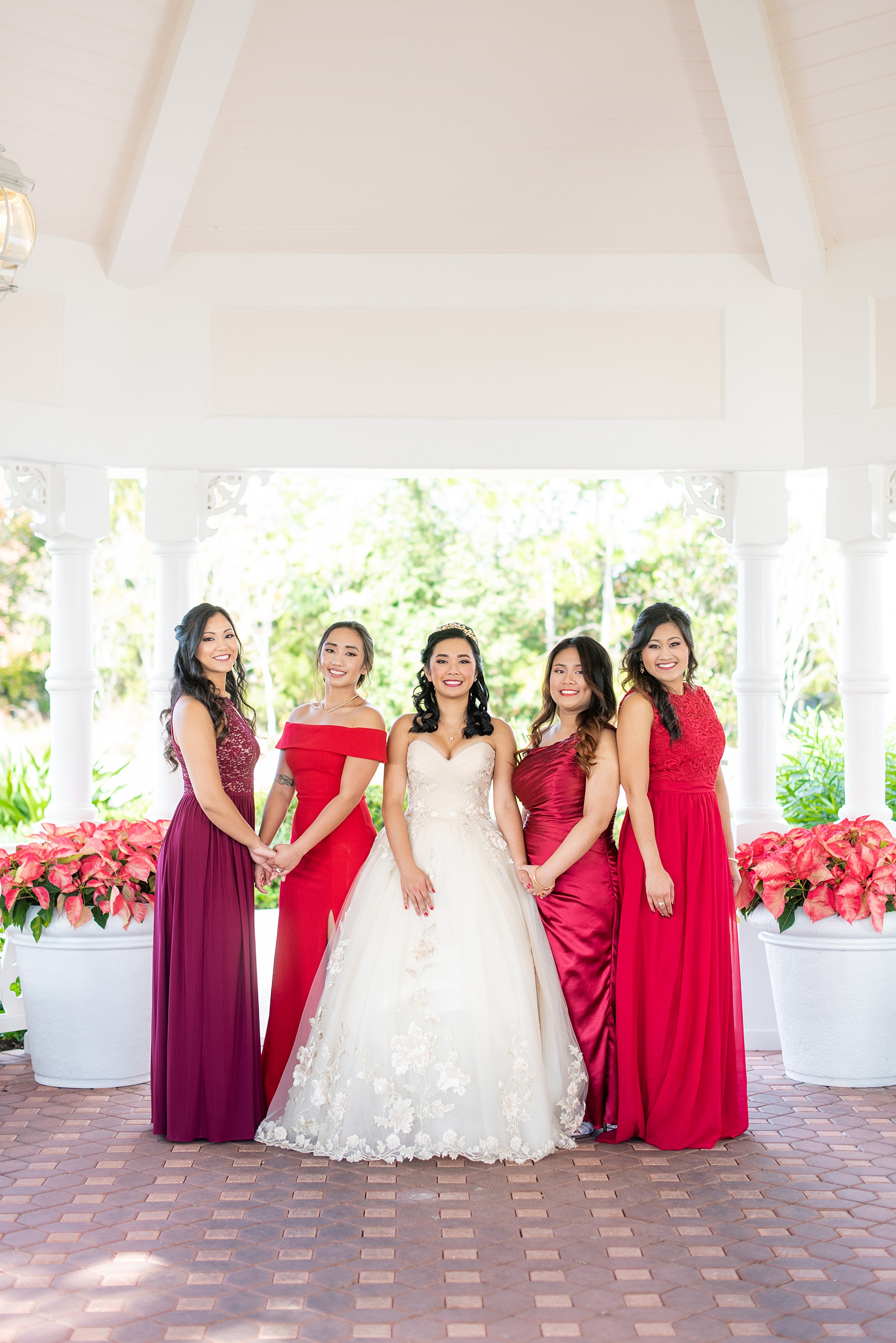Photographs of a Walt Disney World bridal party by Mikkel Paige Photography. The bride chose the venues of the Grand Floridian, Wedding Pavilion and The Contemporary Resort for photos and fun locations. One even overlooked the Magic Kingdom Park! Their dream wedding included red details: the bridesmaids wore mismatched dresses and carried rose bouquets. #disneywedding #disneybride #waltdisneyworld #DisneyWorldWedding #BeautyandtheBeast #redrosewedding