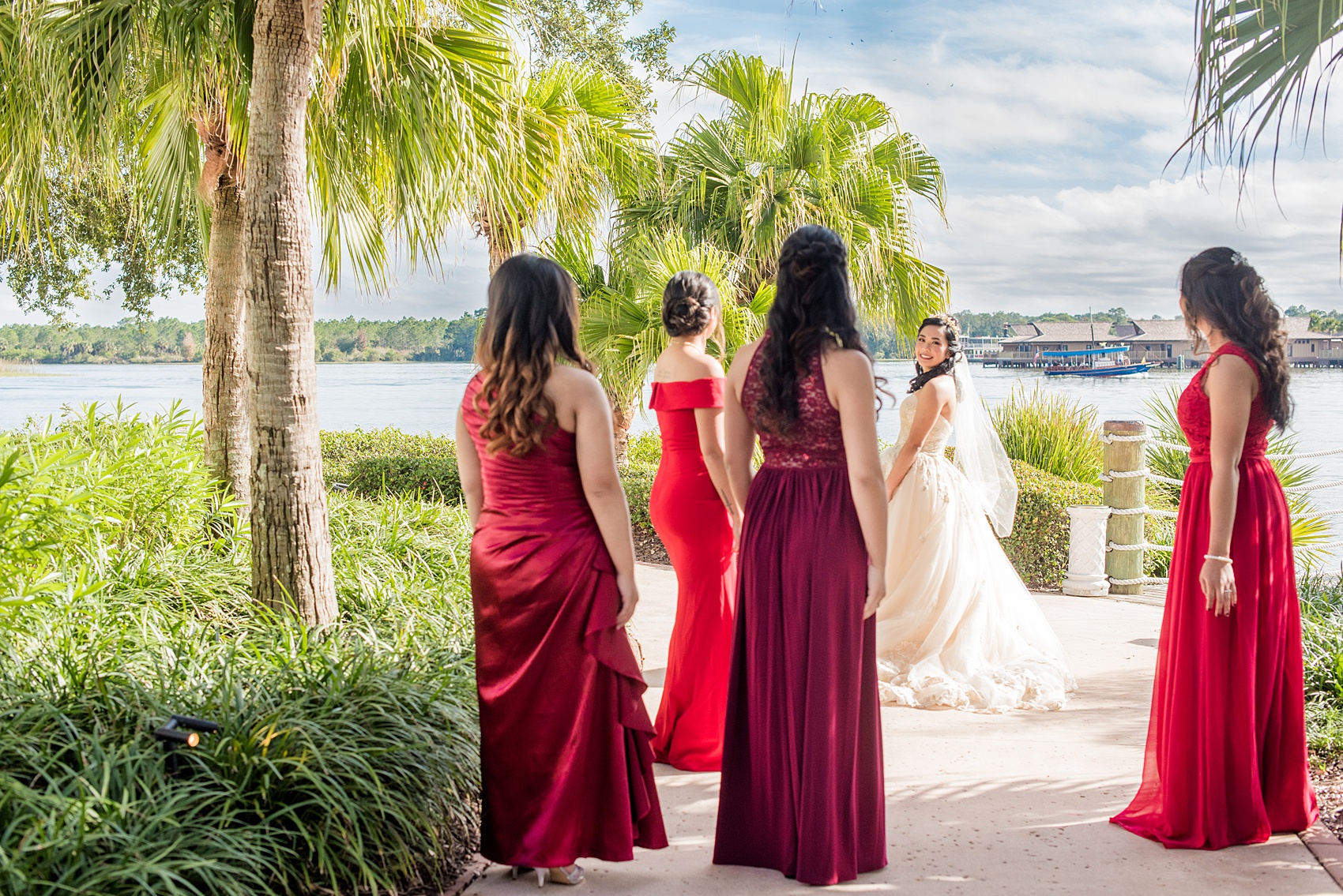 Photographs of a Walt Disney World bridal party by Mikkel Paige Photography. The bride chose the venues of the Grand Floridian, Wedding Pavilion and The Contemporary Resort for photos and fun locations. One even overlooked the Magic Kingdom Park! Their dream wedding included red details: the bridesmaids wore mismatched dresses and carried rose bouquets. #disneywedding #disneybride #waltdisneyworld #DisneyWorldWedding #BeautyandtheBeast #redrosewedding