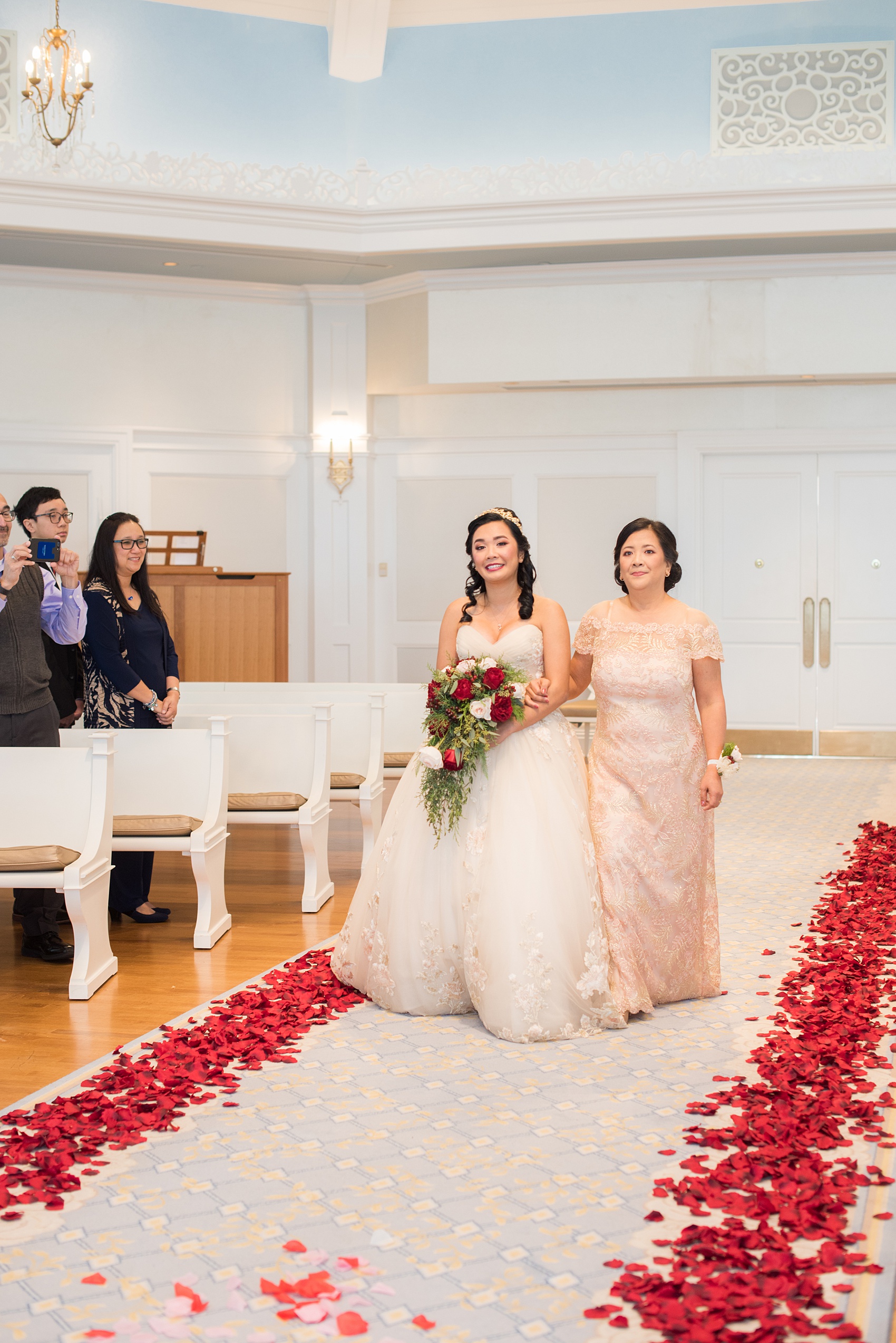 Photographs of a Walt Disney World wedding by Mikkel Paige Photography will give you ideas for a tasteful Beauty and the Beast theme. There was a glass dome with a red rose inside at the start of the ceremony with red rose petals scattered down the aisle for a small, intimate guest list at the Wedding Pavilion next to the Grand Floridian resort. #disneywedding #disneybride #waltdisneyworld #DisneyWorldWedding #DisneyCeremony #DisneyWorldWeddingPavilion