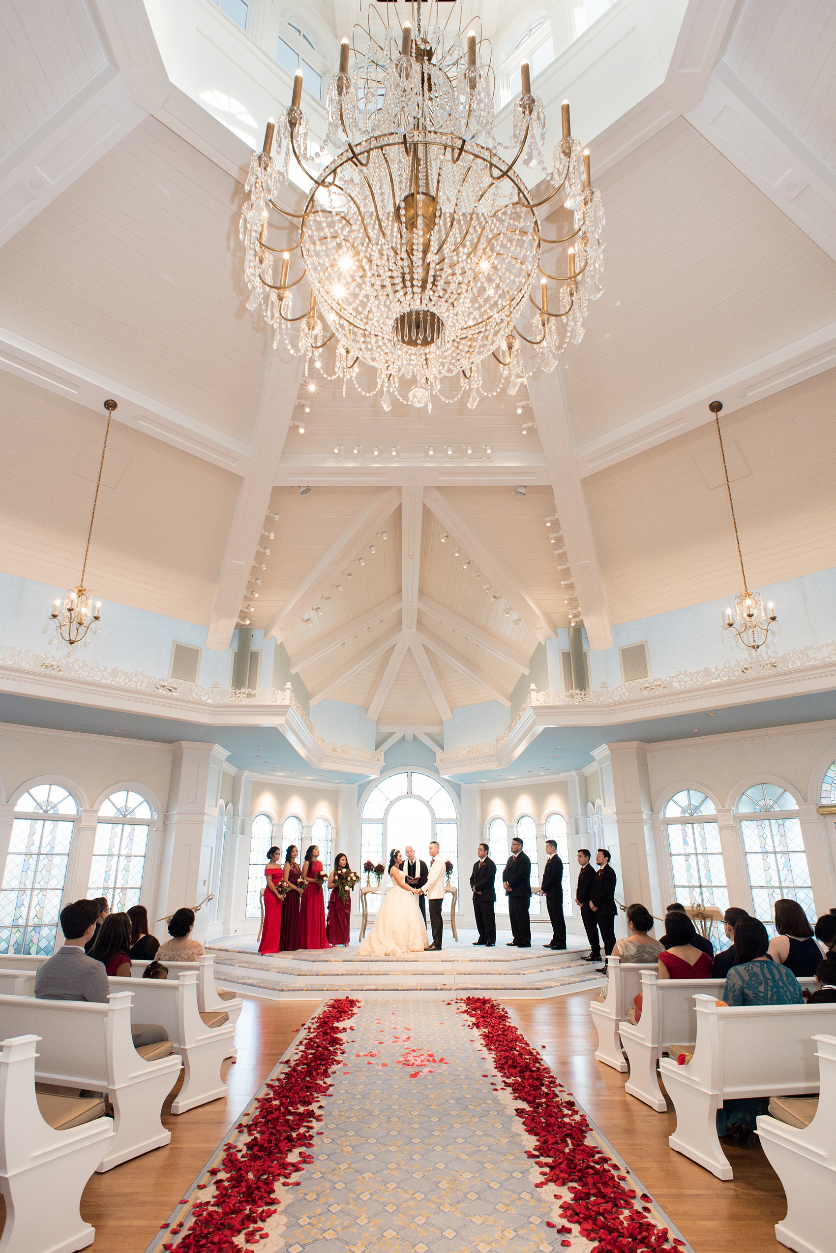 Photographs of a Walt Disney World wedding by Mikkel Paige Photography will give you ideas for a tasteful Beauty and the Beast theme. There was a glass dome with a red rose inside at the start of the ceremony with red rose petals scattered down the aisle for a small, intimate guest list at the Wedding Pavilion next to the Grand Floridian resort. #disneywedding #disneybride #waltdisneyworld #DisneyWorldWedding #DisneyCeremony #DisneyWorldWeddingPavilion