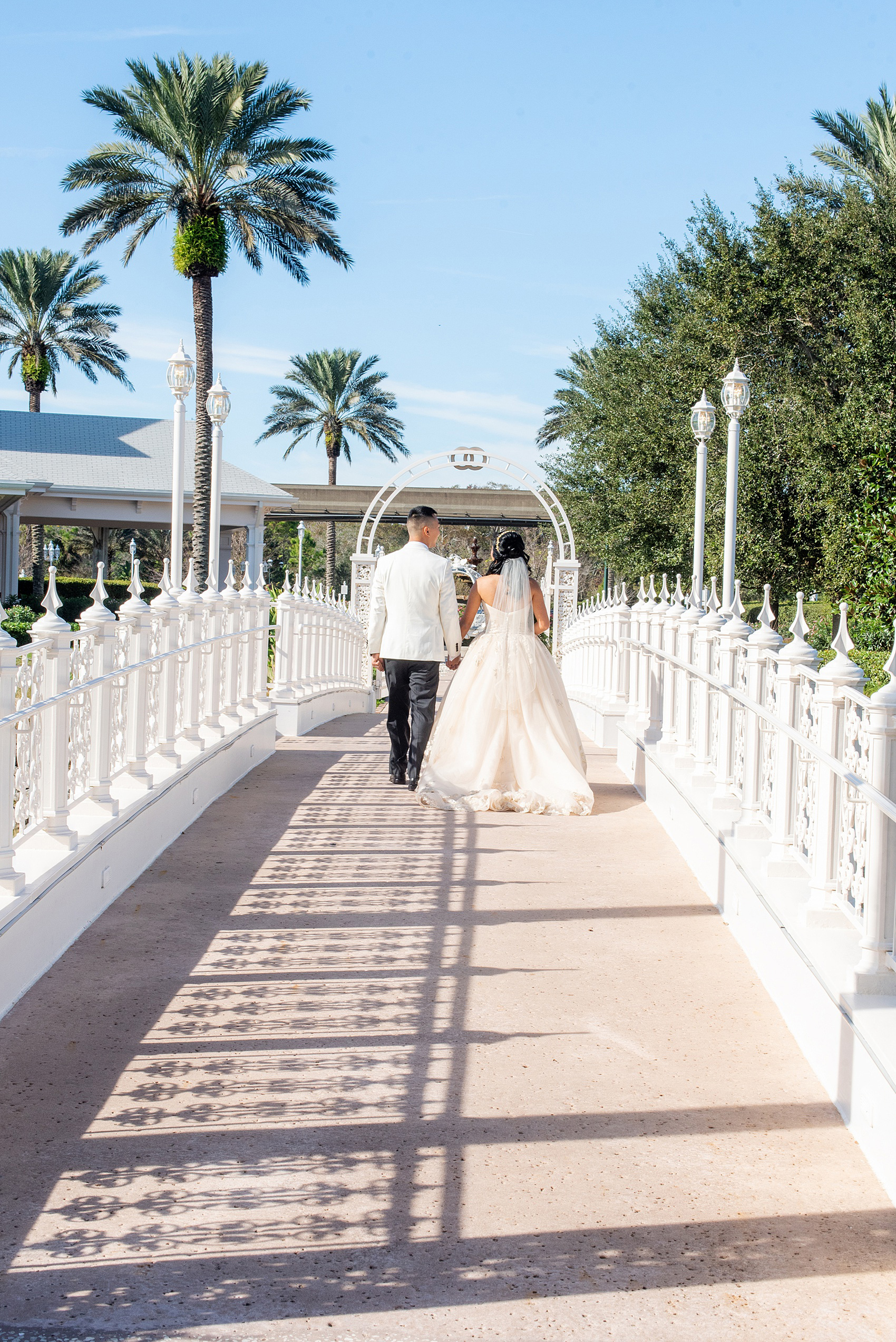 Walt Disney World photographs by Mikkel Paige Photography. The bride and groom had December pictures at the Grand Floridian Resort, Wedding Pavilion and Contemporary Hotel. It had a Beauty and the Beast theme and the bride wore a beautiful rose embroidered dress, befitting of a princess. Her red rose bouquet had holiday greenery and a cascading effect. The groom wore a white tuxedo. #disneywedding #disneybride #waltdisneyworld #DisneyWorldWedding #cascadingbouquet