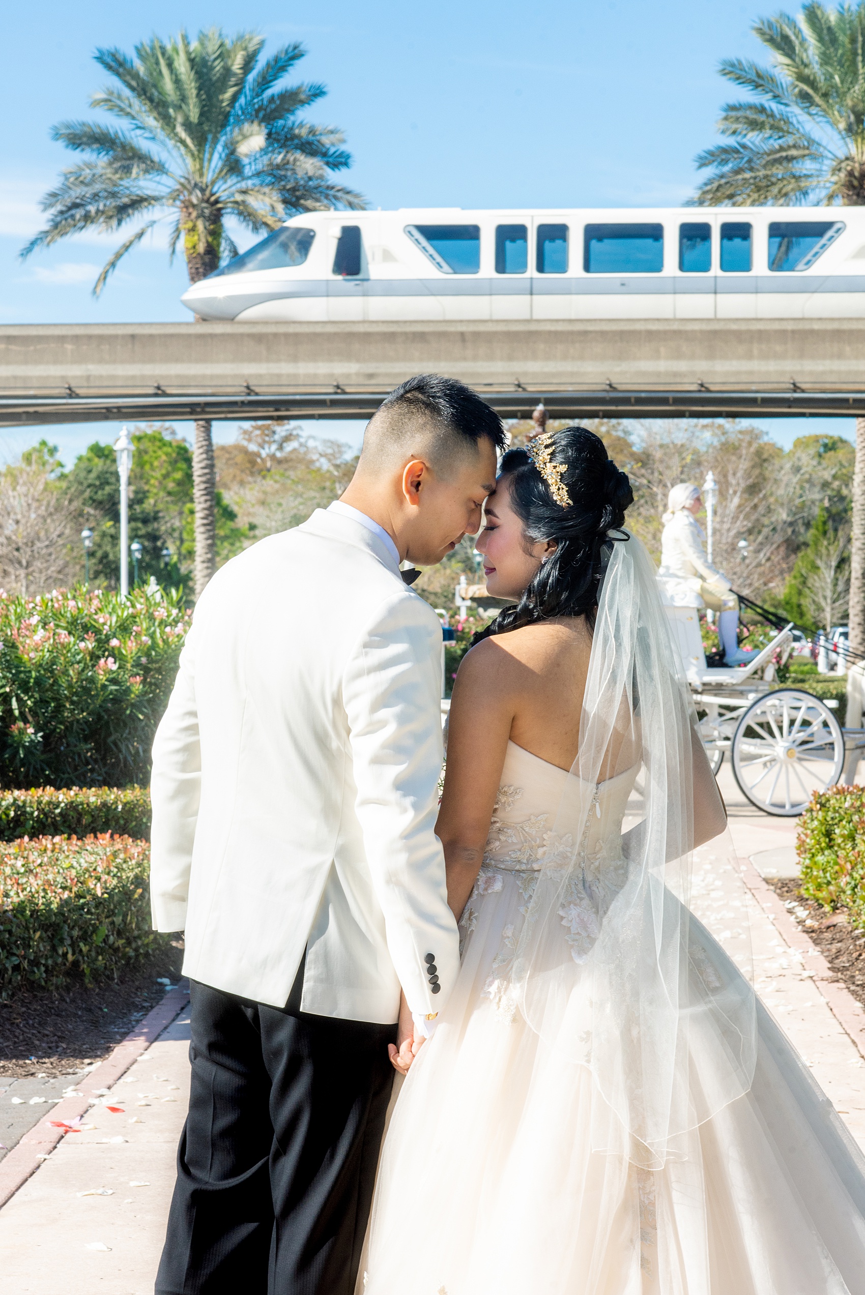 Walt Disney World photographs by Mikkel Paige Photography. The bride and groom had December pictures at the Grand Floridian Resort, Wedding Pavilion and Contemporary Hotel. It had a Beauty and the Beast theme and the bride wore a beautiful rose embroidered dress, befitting of a princess. Her red rose bouquet had holiday greenery and a cascading effect. The groom wore a white tuxedo. #disneywedding #disneybride #waltdisneyworld #DisneyWorldWedding #cascadingbouquet