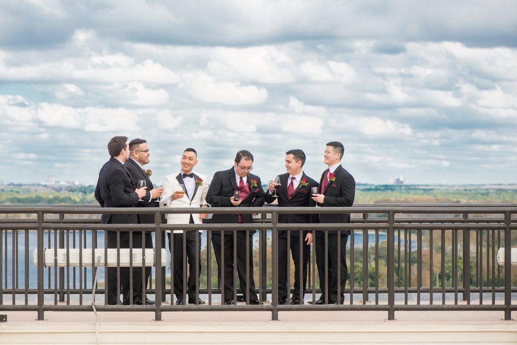 Photographs of a Walt Disney World bridal party by Mikkel Paige Photography. The groom wore a white tuxedo to his wedding venues of the Grand Floridian, Wedding Pavilion and The Contemporary Resort. They all wore rose boutonnieres and marvel comic cufflinks, a small detail that was an awesome way to incorporate a fun idea. #disneywedding #disneybride #waltdisneyworld #DisneyWorldWedding #BeautyandtheBeast #redrosewedding