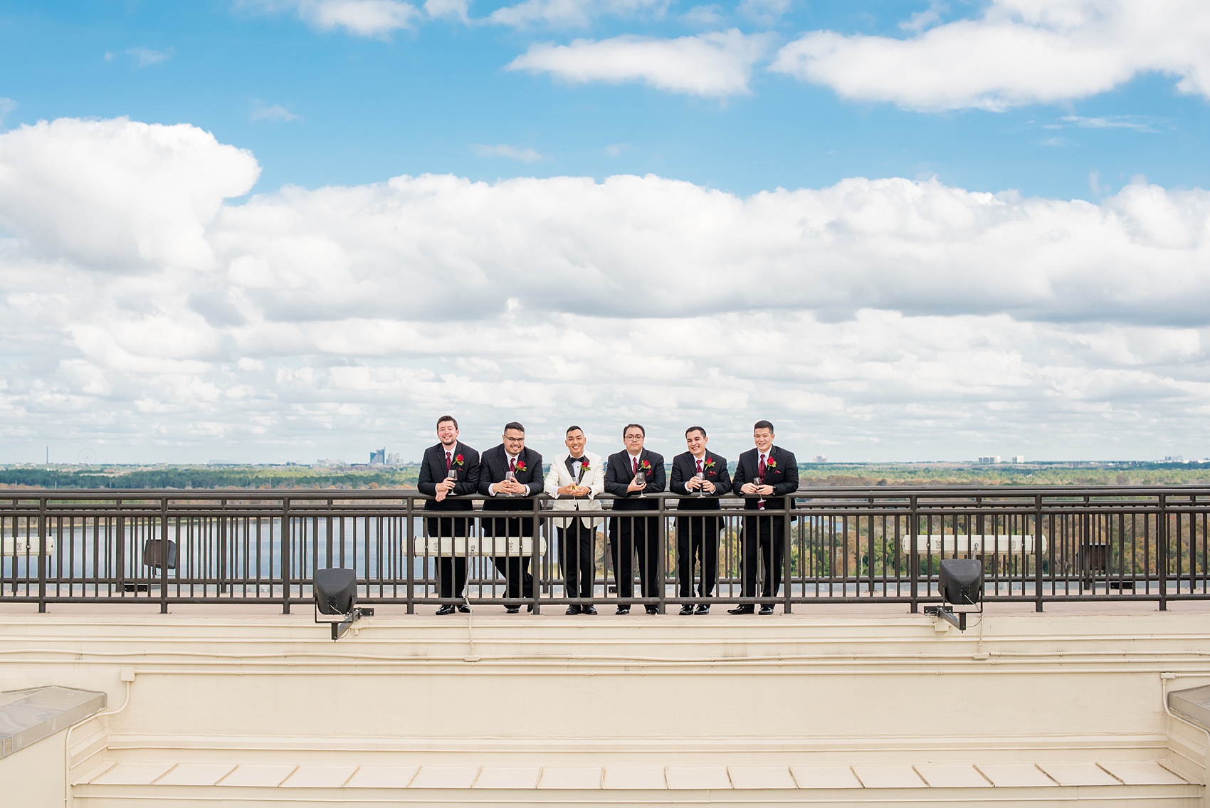 Photographs of a Walt Disney World bridal party by Mikkel Paige Photography. The groom wore a white tuxedo to his wedding venues of the Grand Floridian, Wedding Pavilion and The Contemporary Resort. They all wore rose boutonnieres and marvel comic cufflinks, a small detail that was an awesome way to incorporate a fun idea. #disneywedding #disneybride #waltdisneyworld #DisneyWorldWedding #BeautyandtheBeast #redrosewedding