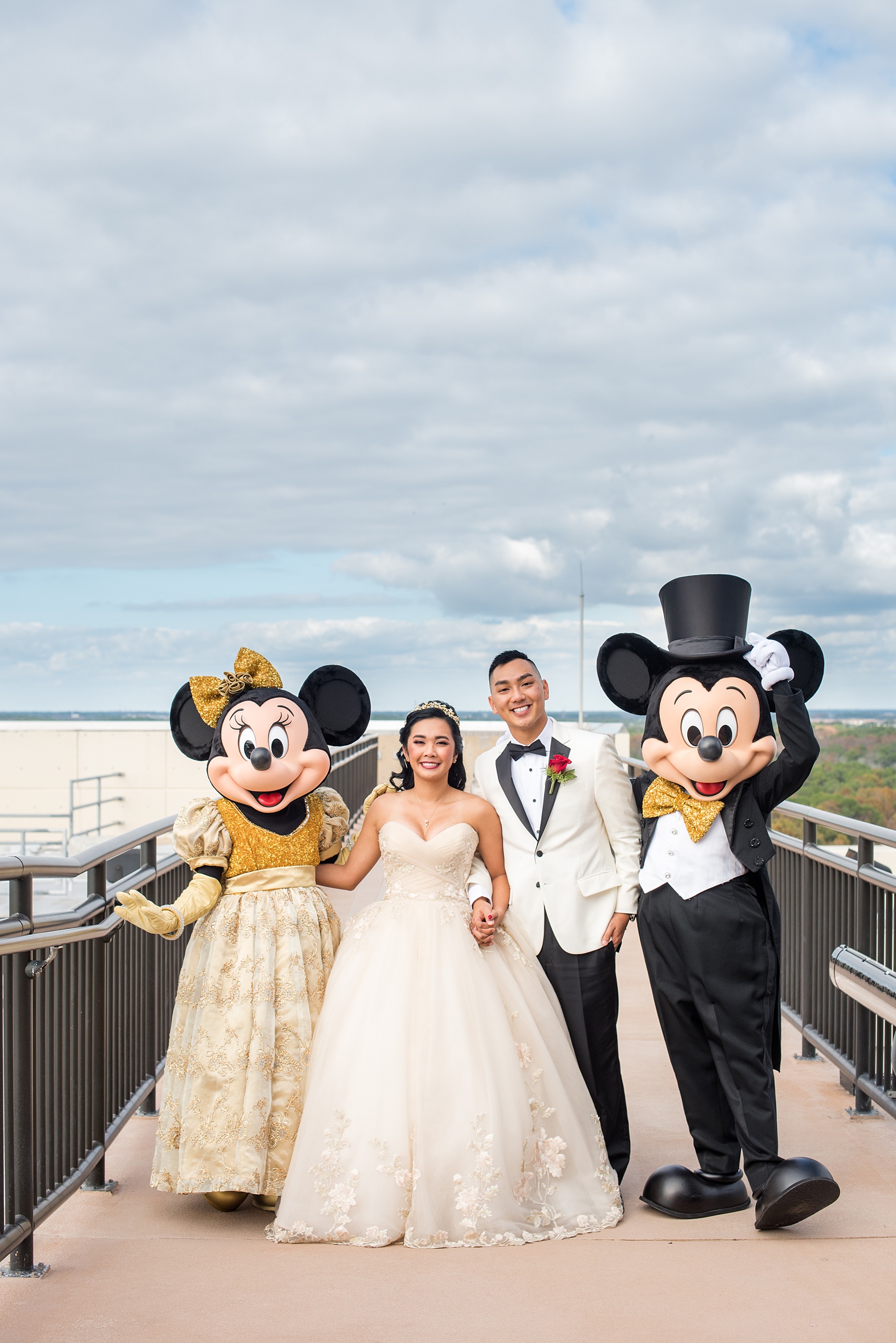 Photographs of a Walt Disney World wedding by Mikkel Paige Photography. The bride and groom had cake cutting help from Mickey Mouse and Minnie Mouse in formal attire! Their reception venue at The Contemporary Resort’s California Grill was great for fun, awesome photos with them. It overlooked the Magic Kingdom Park and Cinderella Castle! Their small, dream day included red rose details and a Beauty and the Beast theme. #disneywedding #DisneyWorldWedding #BeautyandtheBeast #MickeyandMinnie