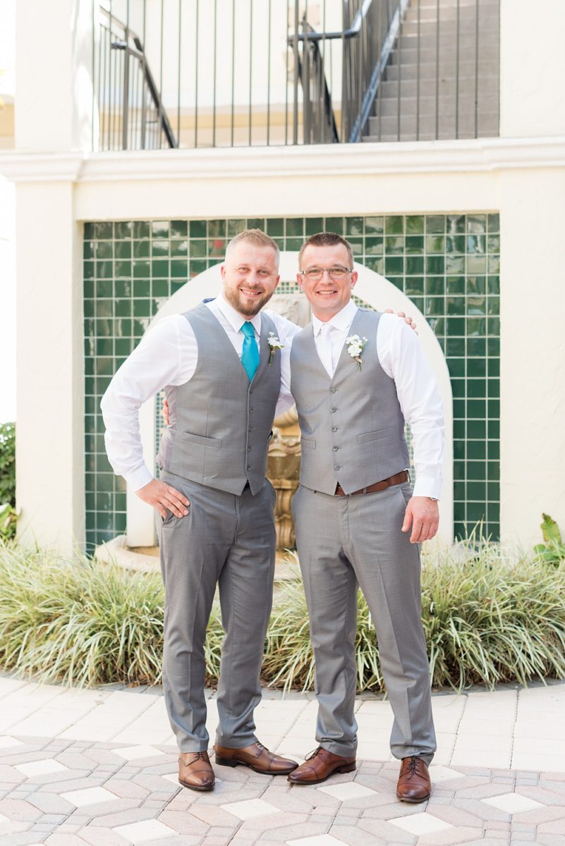 Hub 925 wedding photos at an alternative Orlando wedding venue by Mikkel Paige Photography. The bride, groom and their wedding party posed for a photo by Sand Lake. The bridesmaids wore different shades of teal dresses and groomsmen wore grey slacks and vests. #mikkelpaige #hub925 #orlandoweddingphotographer #orlandoweddingphotos #floridaweddingphotographer #centralfloridawedding #bridalparty #tealbridesmaids #weddingparty