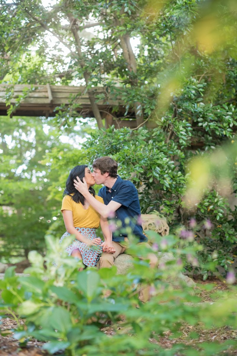 Raleigh engagement photos with murals and spring flowers in the downtown area by Mikkel Paige Photography. The bride and groom choose JC Raulston Arboretum and the Marbles Kids Museum mural for their pictures. There was a special detail of a tiny sapphire in the bride's engagement ring. #DowntownRaleigh #RaleighWeddingPhotographer #mikkelpaige #RaleighPhotographer #RaleighPhotos #RaleighNC #NorthCarolinaPhotographer