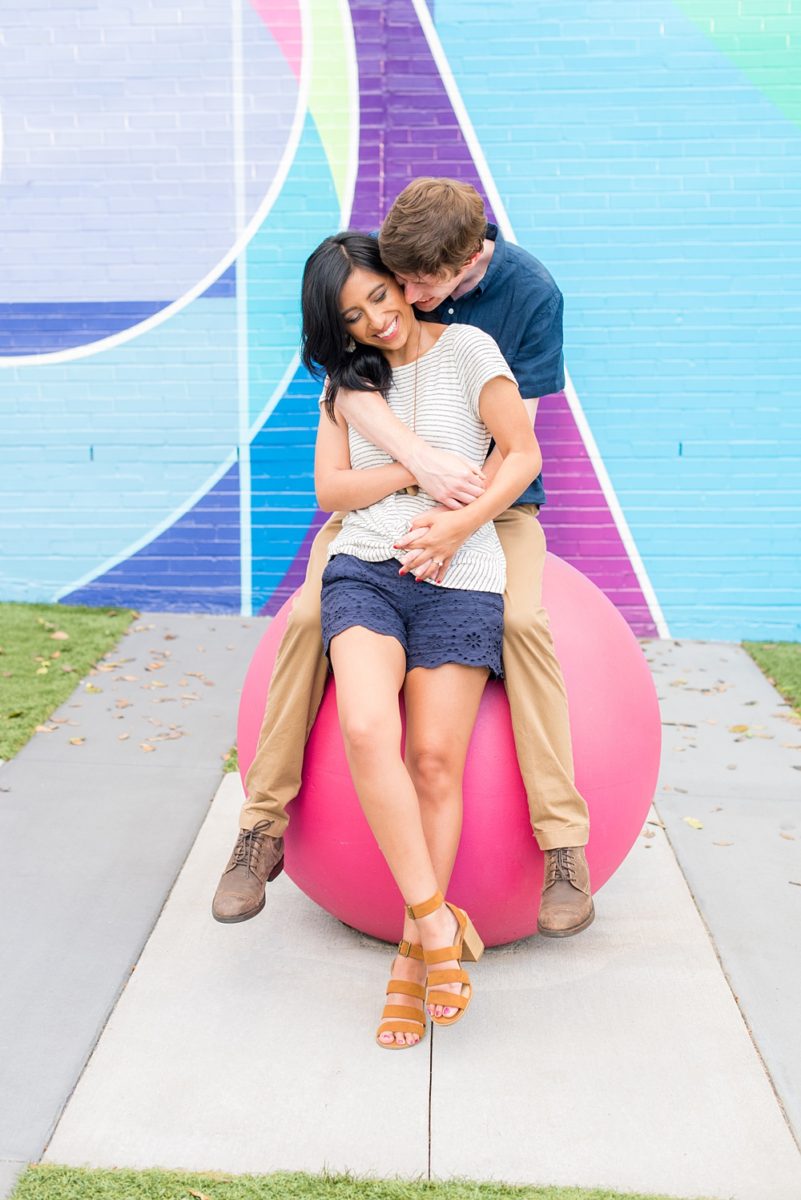 Raleigh engagement photos with murals and spring flowers in the downtown area by Mikkel Paige Photography. The bride and groom choose JC Raulston Arboretum and the Marbles Kids Museum mural for their pictures. #DowntownRaleigh #RaleighWeddingPhotographer #mikkelpaige #RaleighPhotographer #RaleighPhotos #RaleighNC #NorthCarolinaPhotographer