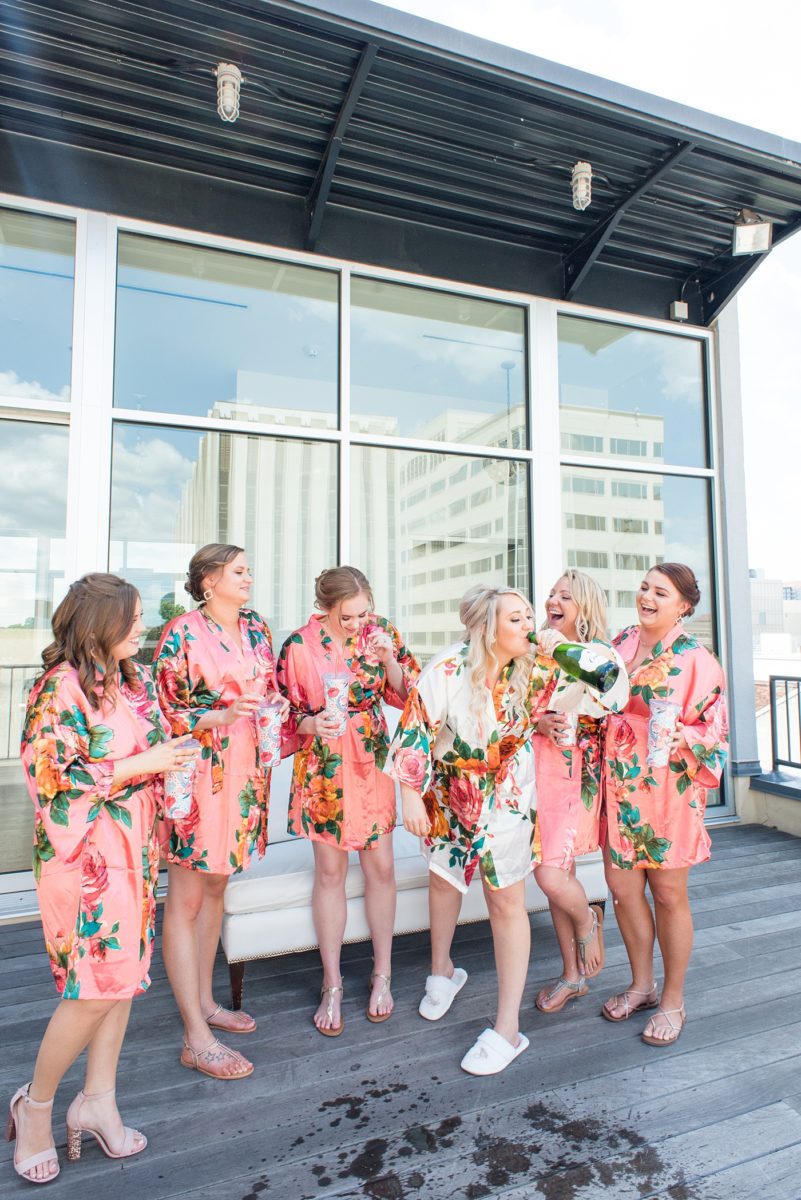 A beautiful spring wedding in Raleigh, North Carolina, at the event venue, The Stockroom at 230 and The Glass Box. Pictures of the bride getting ready with her yorkie dog by their photographer, Mikkel Paige Photography. Their hot pink and aqua colors were perfect for May as the bridesmaids celebrated with a champagne toast in floral robes. #MikkelPaige #DowntownRaleigh #RaleighWedding #RaleighVenue #TheStockroomat230 #bridesmaidsrobes #weddinggettingready