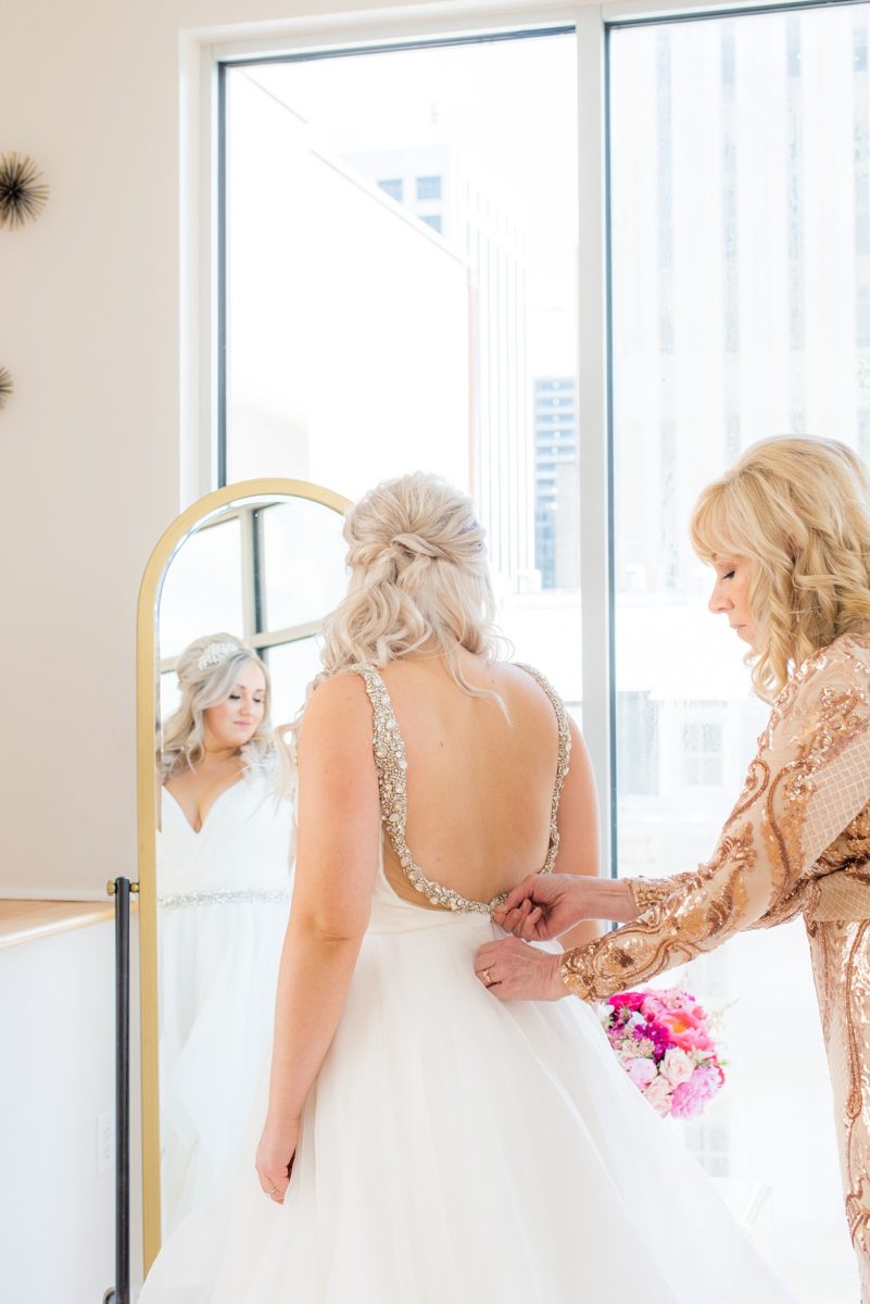 A beautiful spring wedding in Raleigh, North Carolina, at the event venue, The Stockroom at 230 and The Glass Box. Pictures of the bride getting ready with her yorkie dog by their photographer, Mikkel Paige Photography. Their hot pink and aqua colors were perfect for May as the bridesmaids celebrated with a champagne toast in floral robes. #MikkelPaige #DowntownRaleigh #RaleighWedding #RaleighVenue #TheStockroomat230 #bridesmaidsrobes #weddinggettingready