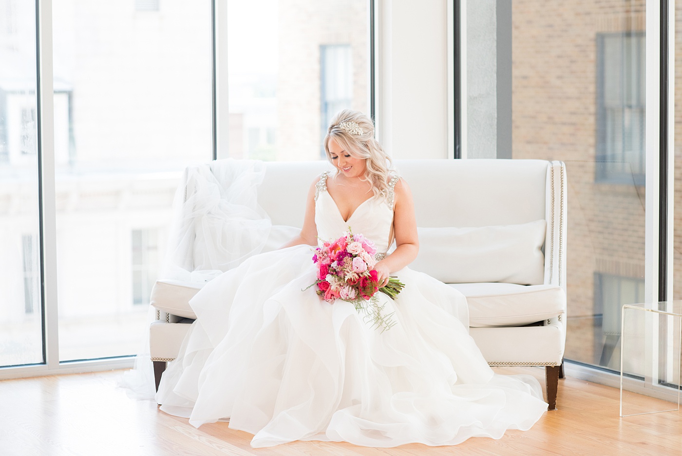 A beautiful spring wedding in Raleigh, North Carolina, at the event venue, The Stockroom at 230 and The Glass Box. Pictures of the bride getting ready with her yorkie dog by their photographer, Mikkel Paige Photography. Their hot pink and aqua colors were perfect for May as the bridesmaids celebrated with a champagne toast in floral robes. #MikkelPaige #DowntownRaleigh #RaleighWedding #RaleighVenue #TheStockroomat230 #bridesmaidsrobes #weddinggettingready