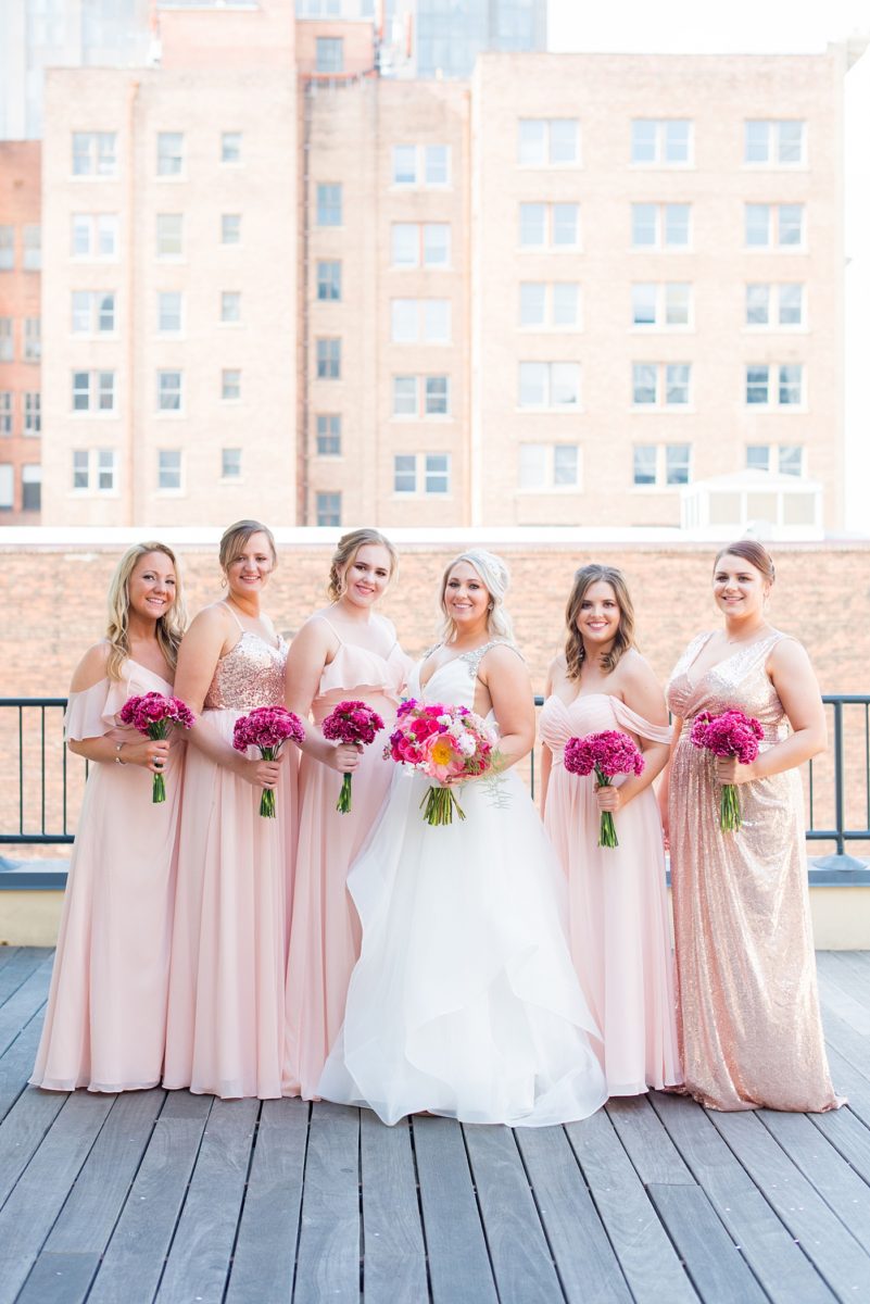 Raleigh wedding photographer, Mikkel Paige Photography, pictures of mismatched pink bridesmaids in downtown Raleigh, North Carolina at the event venue The Stockroom at 230, The Glass Box, and capital building. Their hot pink peony + carnation bouquets were perfect for a spring May celebration. #MikkelPaige #DowntownRaleigh #RaleighWedding #RaleighVenue #TheStockroomat230 #capitalcity #peonies #carnations #pinkbridesmaids #bridalpartyphotos #weddingparty