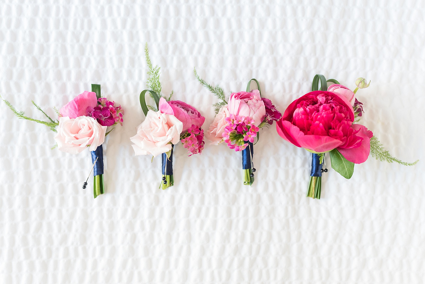 Raleigh wedding photographer, Mikkel Paige Photography, pictures of pink boutonnieres by The English Garden Raleigh for a wedding downtown in Raleigh, North Carolina at the event venue The Stockroom at 230. The bright colors and hot pink boutonnieres were perfect for a spring May celebration. #MikkelPaige #DowntownRaleigh #RaleighWedding #RaleighVenue #TheStockroomat230 #capitalcity #groomsmen #boutonnieres #bluesuits #floralties #groomstyle