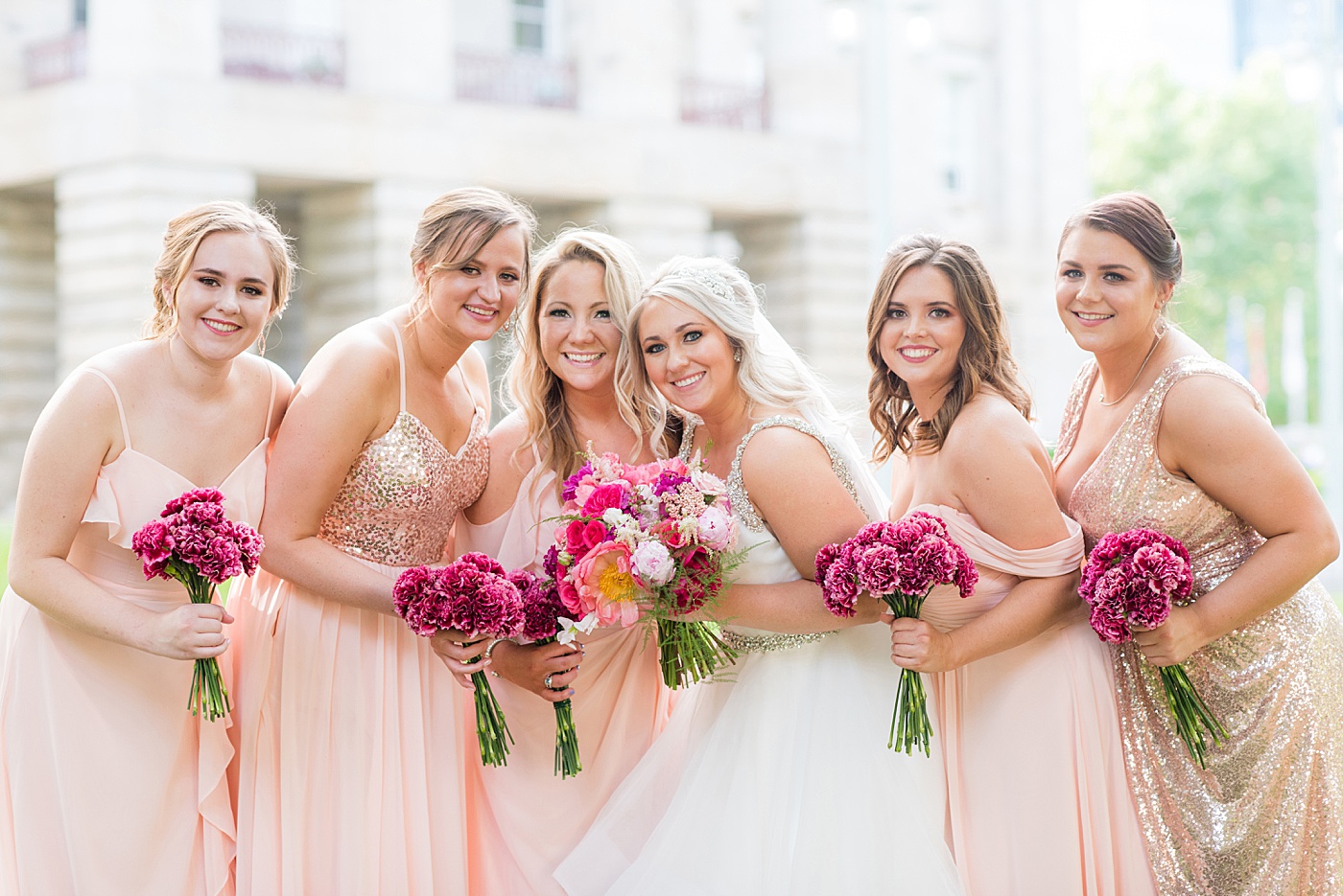 Raleigh wedding photographer, Mikkel Paige Photography, pictures of mismatched pink bridesmaids in downtown Raleigh, North Carolina at the event venue The Stockroom at 230, The Glass Box, and capital building. Their hot pink peony + carnation bouquets were perfect for a spring May celebration. #MikkelPaige #DowntownRaleigh #RaleighWedding #RaleighVenue #TheStockroomat230 #capitalcity #peonies #carnations #pinkbridesmaids #bridalpartyphotos #weddingparty