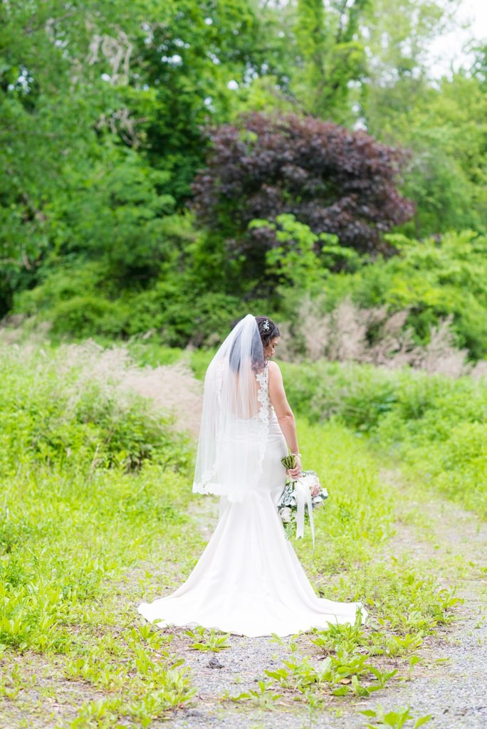 Westchester wedding photography at a beautiful outdoor and indoor venue called Crabtree's Kittle House. Photos by Mikkel Paige Photography. The bride's style was classic, wearing a deep v-neck lace gown by Paloma Blanca from Kleinfeld Bridal and white veil with lace edge. #mikkelpaige #westchestervenue #westchesterphotography #crabtreeskittlehouse #laceweddingdress #summerwedding #bridestyle