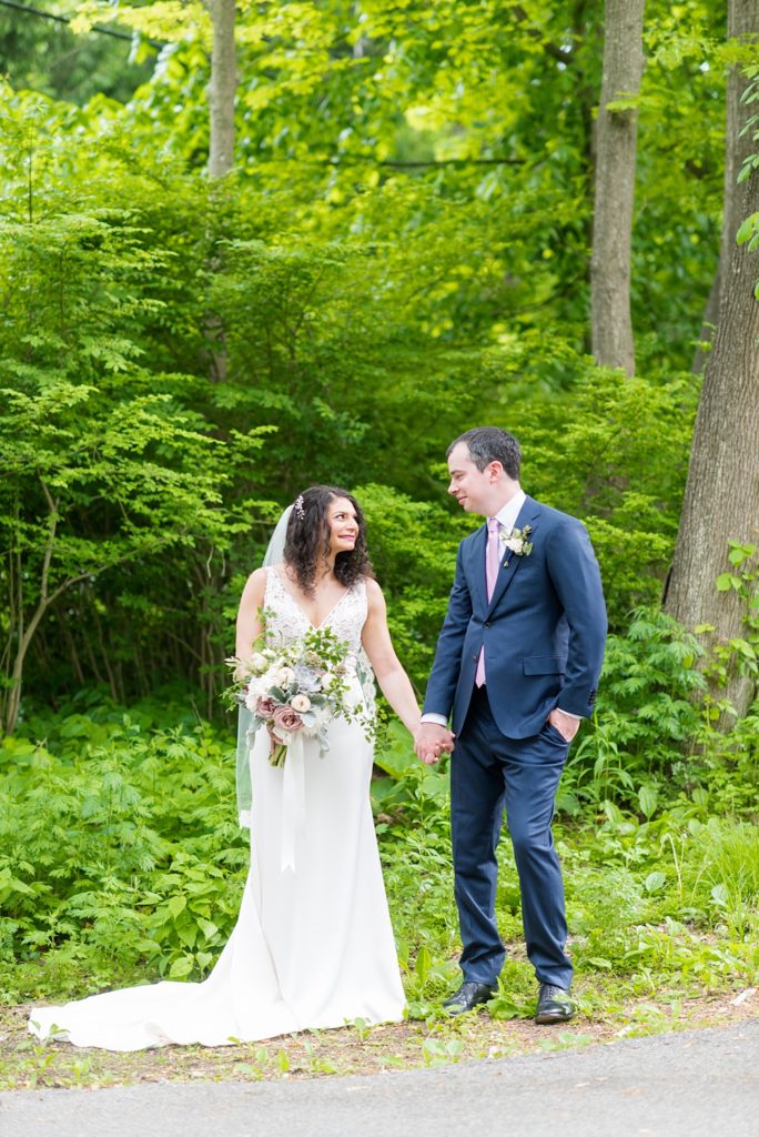 Westchester wedding photography at a beautiful outdoor and indoor venue called Crabtree's Kittle House. Photos by Mikkel Paige Photography. The bride and groom looked classic in a blue suit and v-neck summer lace gown with a deep back. They had a bouquet and boutonniere with poppy pods, scabiosas and roses in a purple + green palette. #mikkelpaige #westchestervenue #westchesterphotography #crabtreeskittlehouse #bridestyle #Maywedding #brideandgroom