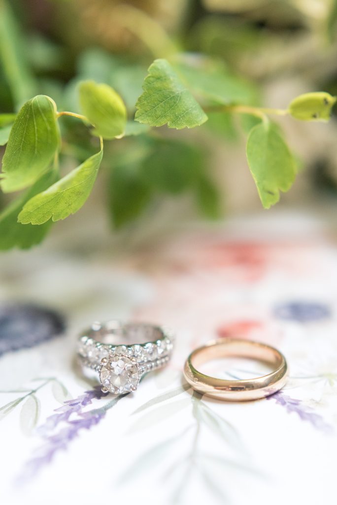 Westchester wedding photography at a beautiful outdoor and indoor venue called Crabtree's Kittle House. Photos by Mikkel Paige Photography. This detail photo shows the bride and groom's diamond and gold wedding bands with their flowers and watercolor invitation envelope liner. #mikkelpaige #westchestervenue #westchesterphotography #crabtreeskittlehouse #summerwedding #weddingrings #diamondring