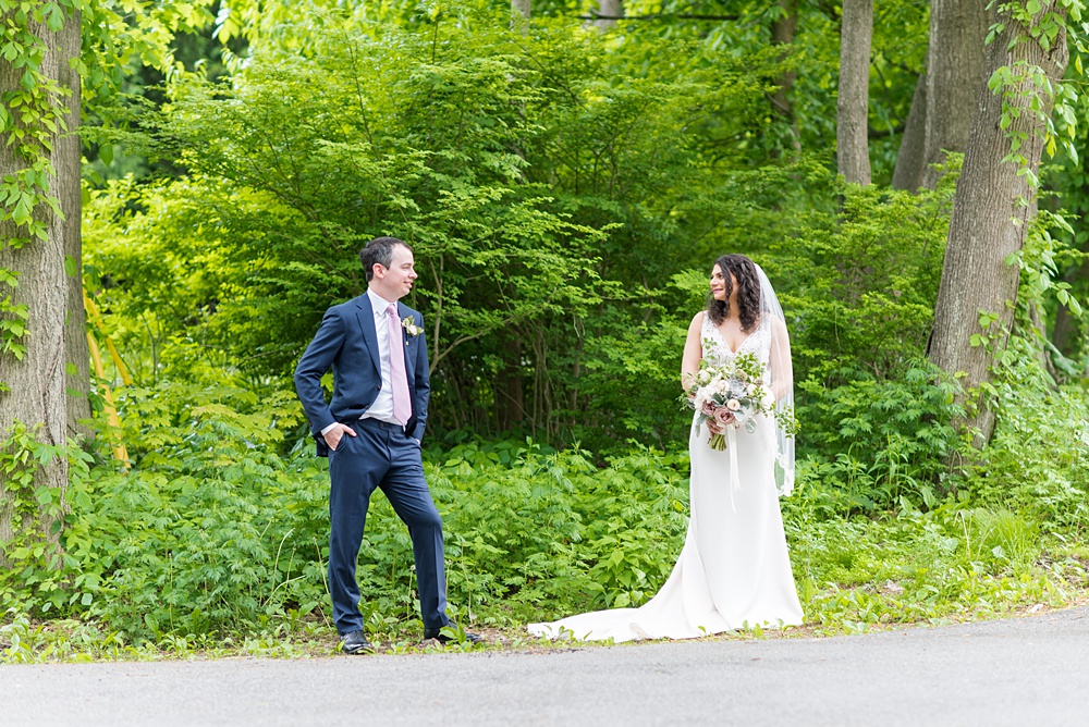 Westchester wedding photography at a beautiful outdoor and indoor venue called Crabtree's Kittle House. Photos by Mikkel Paige Photography. The bride and groom looked classic in a blue suit and v-neck summer lace gown with a deep back. They had a bouquet and boutonniere with poppy pods, scabiosas and roses in a purple + green palette. #mikkelpaige #westchestervenue #westchesterphotography #crabtreeskittlehouse #bridestyle #Maywedding #brideandgroom