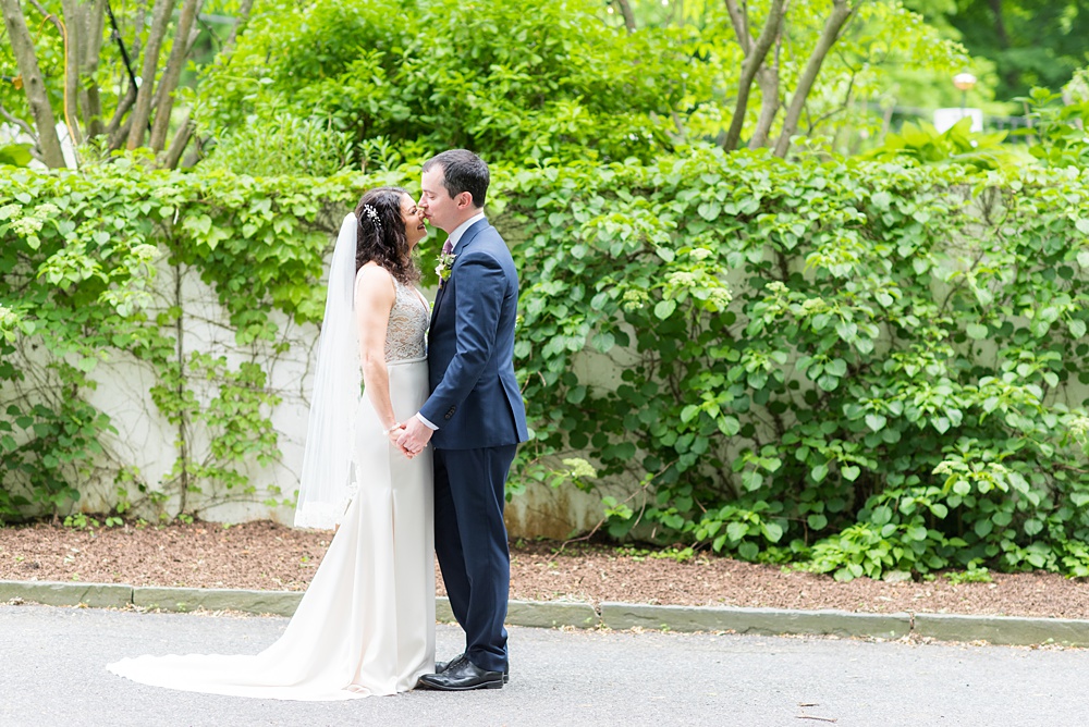 Westchester wedding photography at a beautiful outdoor and indoor venue called Crabtree's Kittle House. Photos by Mikkel Paige Photography. The bride and groom looked classic in a blue suit and v-neck summer lace gown with a deep back. They had a bouquet and boutonniere with poppy pods, scabiosas and roses in a purple + green palette. #mikkelpaige #westchestervenue #westchesterphotography #crabtreeskittlehouse #bridestyle #Maywedding #brideandgroom