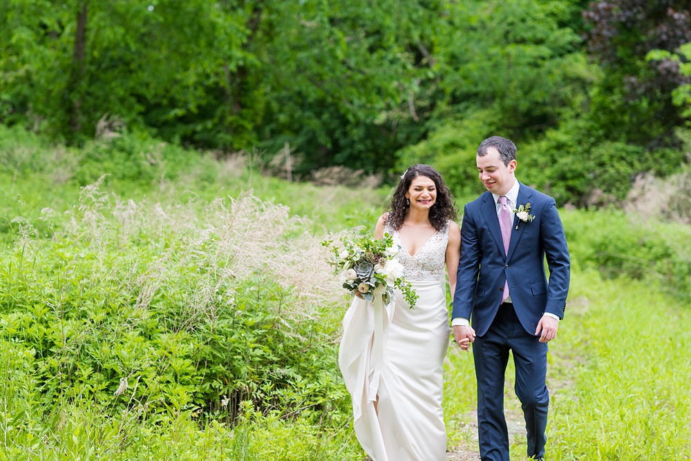 Westchester wedding photography at a beautiful outdoor and indoor venue called Crabtree's Kittle House. Photos by Mikkel Paige Photography. The bride and groom looked classic in a blue suit and v-neck summer lace gown with a deep back. They had a bouquet and boutonniere with poppy pods, scabiosas and roses in a purple + green palette. #mikkelpaige #westchestervenue #westchesterphotography #crabtreeskittlehouse #bridestyle #Maywedding #brideandgroom