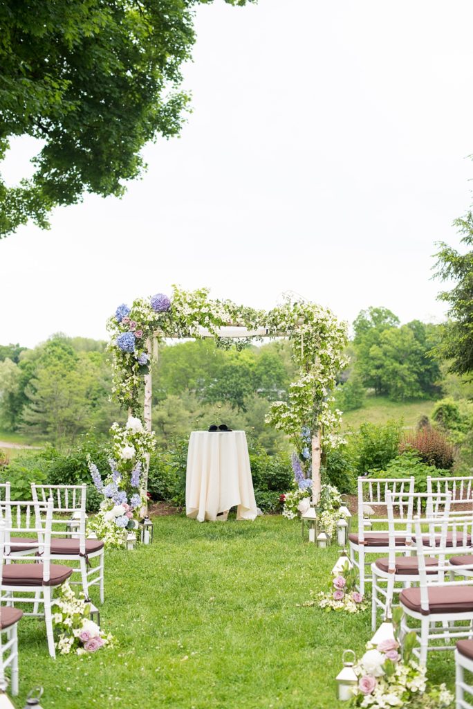 Westchester wedding photography by Mikkel Paige Photography at a beautiful venue called Crabtree's Kittle House. Their outdoor ceremony had Jewish traditions like breaking of a glass and their friend officiated. Purple and white flowers, including roses and dogwoods, lined the aisle with lanterns and greenery. #mikkelpaige #westchestervenue #westchesterphotography #crabtreeskittlehouse #summerwedding #weddingceremony #weddingtent