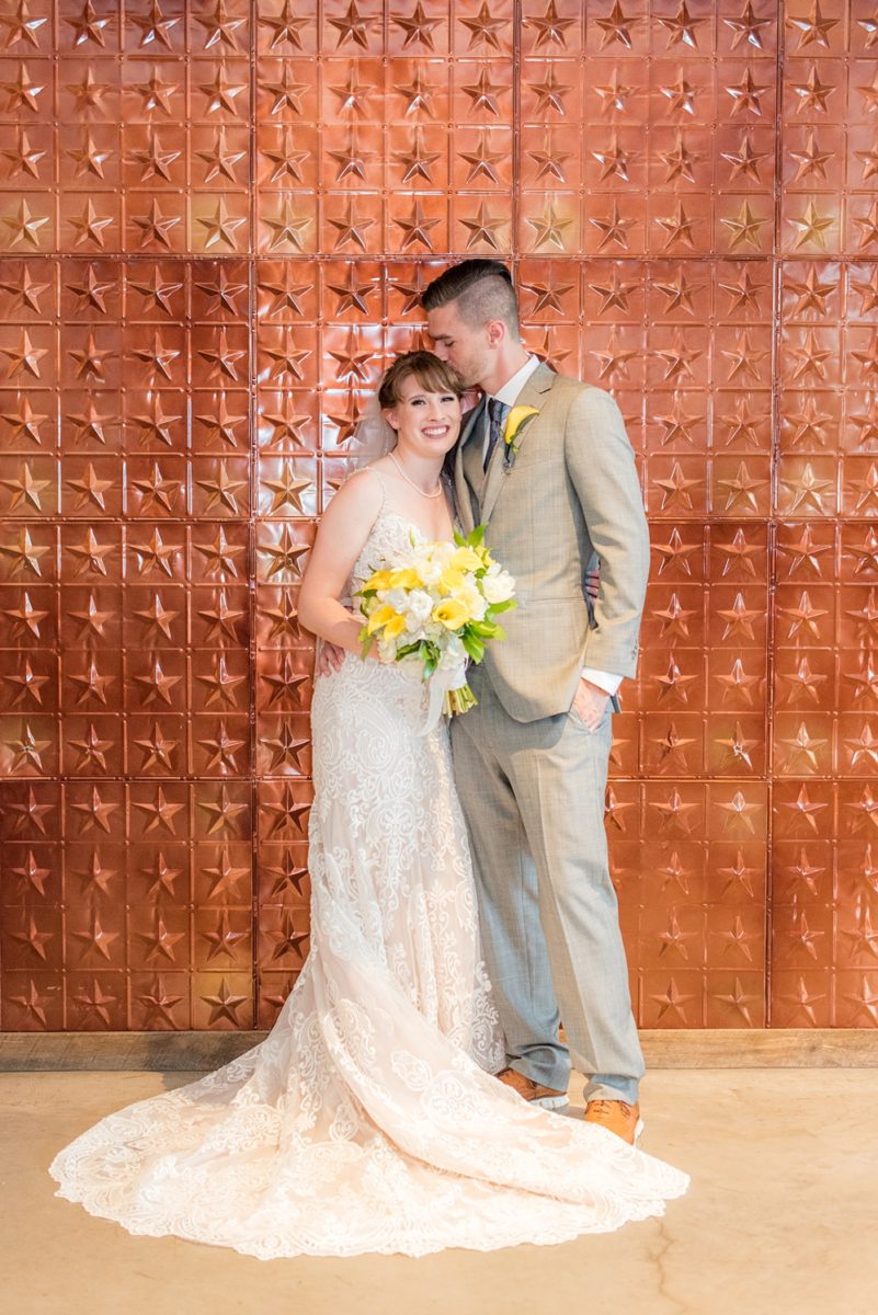 Pictures at a Durham, North Carolina wedding venue by Mikkel Paige Photography. The Rickhouse was the perfect indoor space for the bride and groom's ceremony and reception with an iconic copper stars wall. The couple chose fun yellow and blue colors for beautiful reception decor. #mikkelpaige #therickhouse #durhamweddingphotos #durhamwedding #northcarolinaweddingphotographer #durhamweddingphotographer #blueandyellow #summerwedding #copperstars
