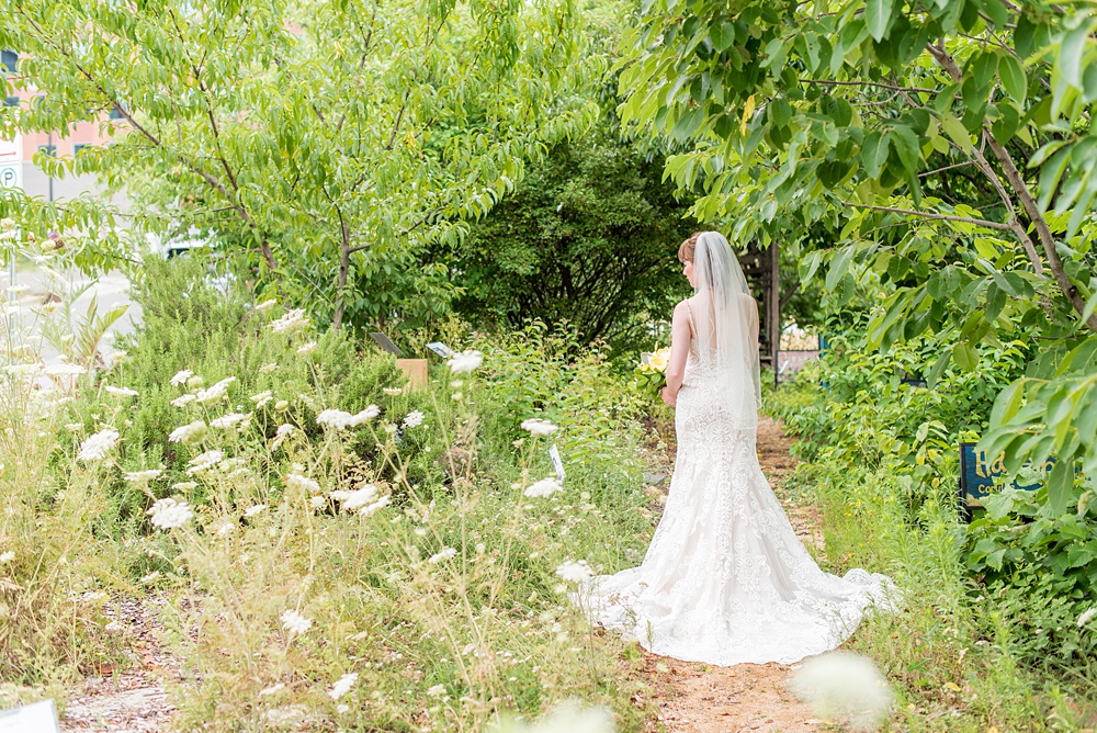 Pictures at a Durham, North Carolina wedding venue by Mikkel Paige Photography. The Rickhouse was the perfect indoor space for the bride and groom's ceremony + reception. They got ready at 21c Museum hotel and took beautiful outdoor photos in the summer sun. The bride chose yellow for her bouquet and a lace v-neck gown for her style. #mikkelpaige #therickhouse #durhamweddingphotos #durhamwedding #northcarolinaweddingphotographer #durhamweddingphotographer #blueandyellow #summerwedding #lacegown