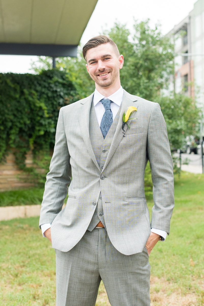 Pictures at a Durham, North Carolina wedding venue by Mikkel Paige Photography. The Rickhouse was the perfect indoor space for the ceremony + reception. The couple got ready at 21c Museum hotel and took beautiful outdoor photos. Groom chose yellow for a calla lily boutonniere and gray three piece suit with custom liner, blue tie + brown shoes. #mikkelpaige #therickhouse #durhamweddingphotos #durhamwedding #northcarolinaweddingphotographer #durhamweddingphotographer #groomstyle #threepiecesuit