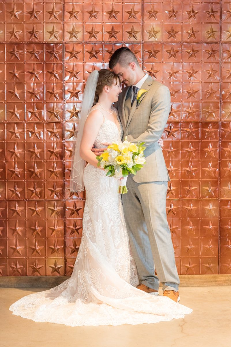 Pictures at a Durham, North Carolina wedding venue by Mikkel Paige Photography. The Rickhouse was the perfect indoor space for the bride and groom's ceremony and reception with an iconic copper stars wall. The couple chose fun yellow and blue colors for beautiful reception decor. #mikkelpaige #therickhouse #durhamweddingphotos #durhamwedding #northcarolinaweddingphotographer #durhamweddingphotographer #blueandyellow #summerwedding #copperstars