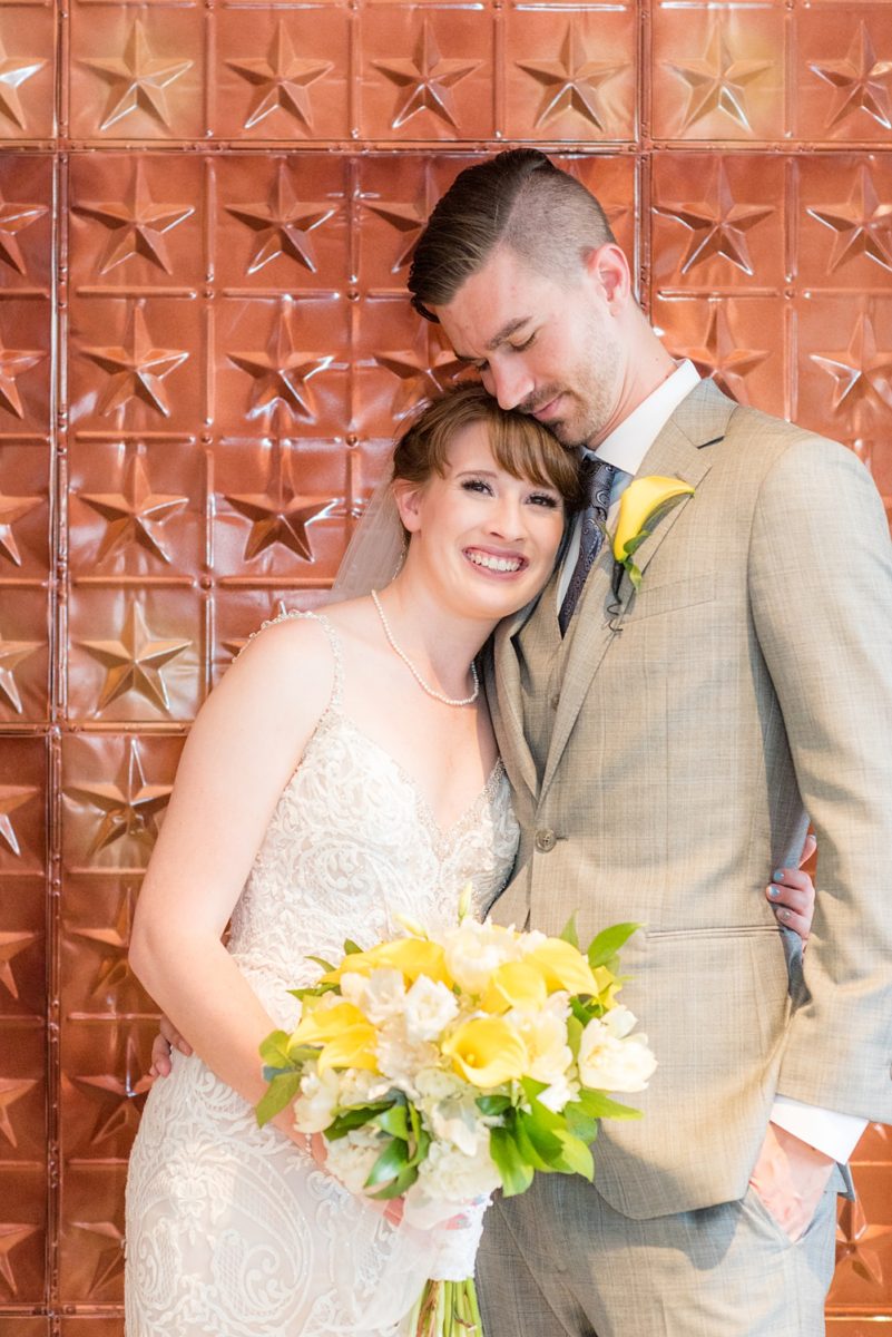 Pictures at a Durham, North Carolina wedding venue by Mikkel Paige Photography. The Rickhouse was the perfect indoor space for the bride and groom's ceremony and reception with an iconic copper stars wall. The couple chose fun yellow and blue colors for beautiful reception decor. #mikkelpaige #therickhouse #durhamweddingphotos #durhamwedding #northcarolinaweddingphotographer #durhamweddingphotographer #blueandyellow #summerwedding #copperstars