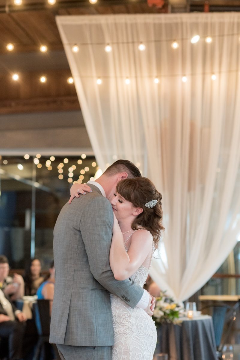 Pictures at a Durham, North Carolina wedding venue by Mikkel Paige Photography. The Rickhouse was the perfect outdoor/indoor space for the bride and groom's celebration. The couple chose fun yellow and blue colors for their summer decor and danced a romantic first dance in this reception photo. #mikkelpaige #therickhouse #durhamweddingphotos #durhamwedding #northcarolinaweddingphotographer #durhamweddingphotographer #firstdance