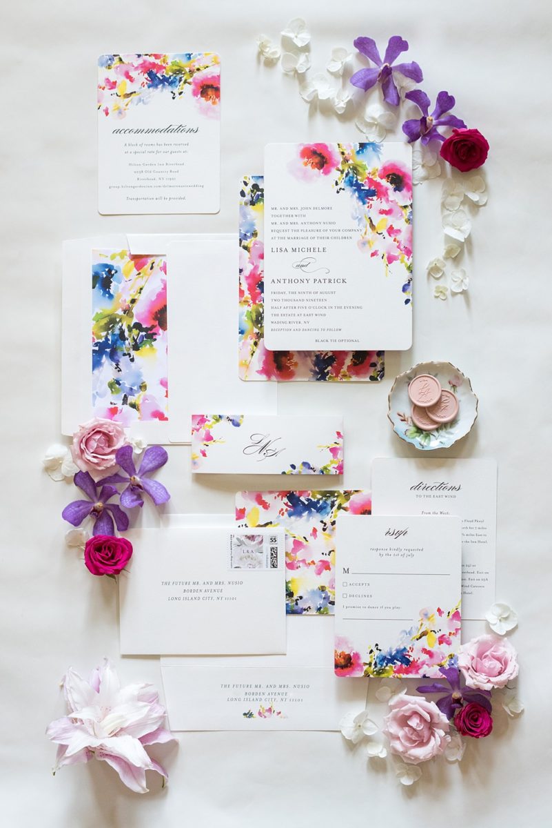 Pictures of a floral wedding invitation and pink wax seal by Mikkel Paige Photography of an East Wind wedding in Wading River, NY on Long Island. The wedding venue has a beautiful outdoor ceremony area and pretty indoor reception space. #mikkelpaige #newyorkweddingphotographer #longislandweddingvenue 