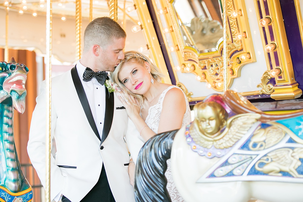 Photos of the bride and groom on a carousel by Mikkel Paige Photography at an East Wind wedding in Wading River, NY on Long Island. The wedding venue has a beautiful outdoor ceremony area and pretty indoor reception space. #mikkelpaige #newyorkweddingphotographer #longislandweddingvenue #summerbride #laceweddinggown #bridestyle #BrideandGroom