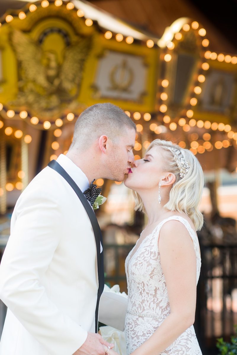 Photos of the bride and groom by a carousel by Mikkel Paige Photography at an East Wind wedding in Wading River, NY on Long Island. The wedding venue has a beautiful outdoor ceremony area and pretty indoor reception space. #mikkelpaige #newyorkweddingphotographer #longislandweddingvenue #summerbride #laceweddinggown #bridestyle #BrideandGroom