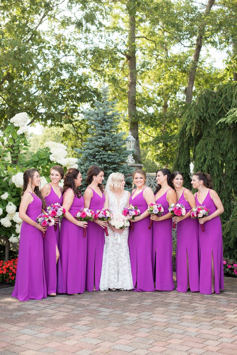 Photos of the bride and bridesmaids in purple gowns by Mikkel Paige Photography at an East Wind wedding in Wading River, NY on Long Island. The wedding venue has a beautiful outdoor ceremony area and pretty indoor reception space. #mikkelpaige #newyorkweddingphotographer #longislandweddingvenue #summerbride #laceweddinggown #bridestyle #purplewedding #bridesmaids #bridalparty