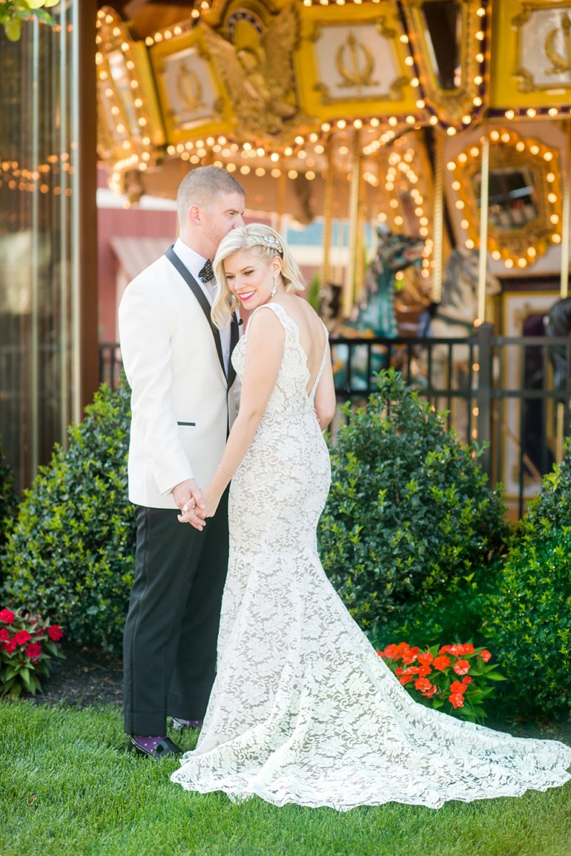 Photos of the bride and groom by a carousel by Mikkel Paige Photography at an East Wind wedding in Wading River, NY on Long Island. The wedding venue has a beautiful outdoor ceremony area and pretty indoor reception space. #mikkelpaige #newyorkweddingphotographer #longislandweddingvenue #summerbride #laceweddinggown #bridestyle #BrideandGroom