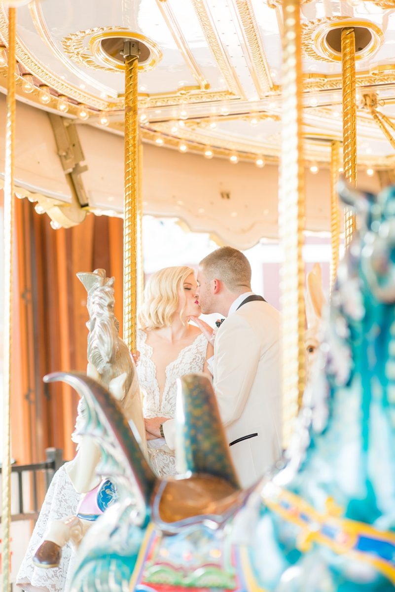 Photos of the bride and groom on a carousel by Mikkel Paige Photography at an East Wind wedding in Wading River, NY on Long Island. The wedding venue has a beautiful outdoor ceremony area and pretty indoor reception space. #mikkelpaige #newyorkweddingphotographer #longislandweddingvenue #summerbride #laceweddinggown #bridestyle #BrideandGroom