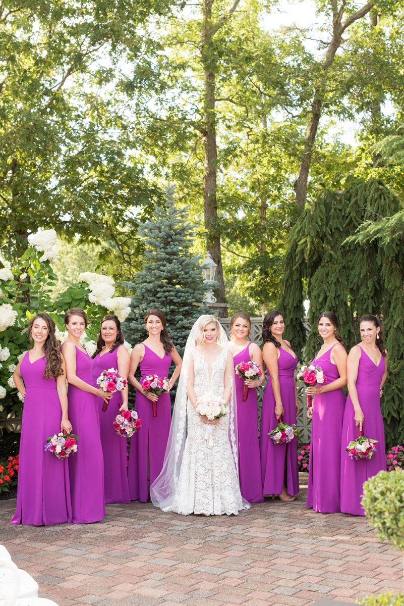 Photos of the bride and bridesmaids in purple gowns by Mikkel Paige Photography at an East Wind wedding in Wading River, NY on Long Island. The wedding venue has a beautiful outdoor ceremony area and pretty indoor reception space. #mikkelpaige #newyorkweddingphotographer #longislandweddingvenue #summerbride #laceweddinggown #bridestyle #purplewedding #bridesmaids #bridalparty