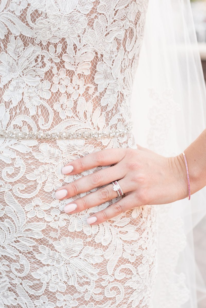 Photos of the bride's rings and her lace gown detail by Mikkel Paige Photography at an East Wind wedding in Wading River, NY on Long Island. The venue has a beautiful outdoor ceremony area and pretty indoor reception space. #mikkelpaige #newyorkweddingphotographer #longislandweddingvenue #summerbride #laceweddinggown #bridestyle #weddingrings #pinkdiamonds