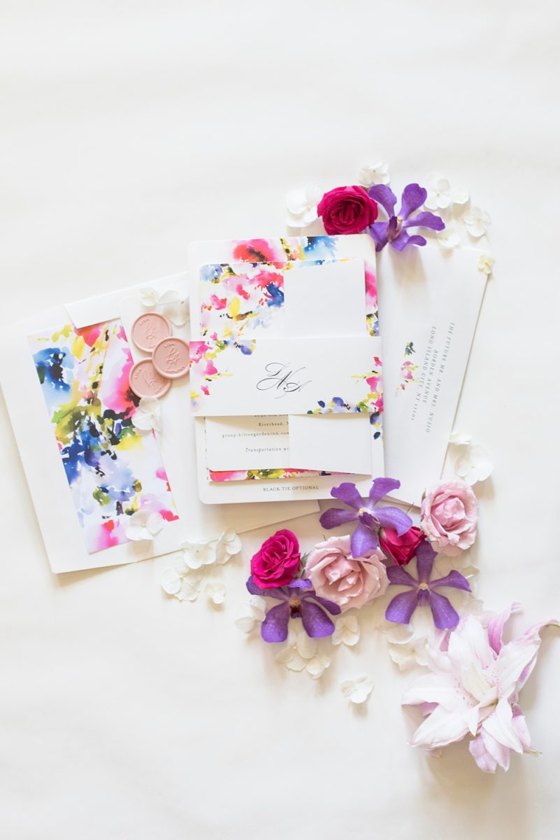 Pictures of a floral wedding invitation and pink wax seal by Mikkel Paige Photography of an East Wind wedding in Wading River, NY on Long Island. The wedding venue has a beautiful outdoor ceremony area and pretty indoor reception space. #mikkelpaige #newyorkweddingphotographer #longislandweddingvenue