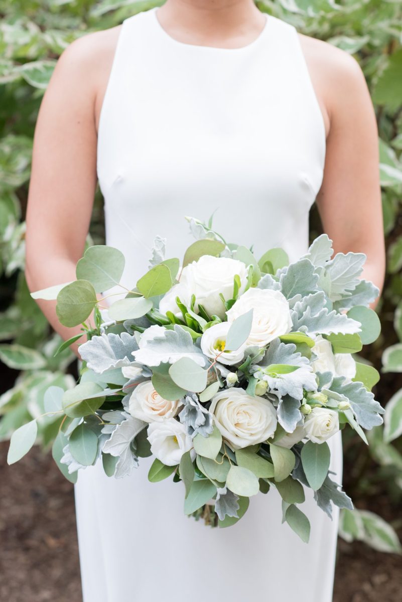 The bride carried a white rose and eucalyptus bouquet for her wedding in Chappaqua, New York at Crabtree's Kittle House. Photos by Mikkel Paige Photography. This venue in Westchester County is near the Hudson Valley and NYC. She wore an elegant, form-fitting white gown with open back with her hair braided and in a low bun. #mikkelpaige #hudsonvalleyweddings #crabtreeskittlehouse #fallwedding #westchestervenues #bridestyle #elegantbride #filipinobride #whitebouquet