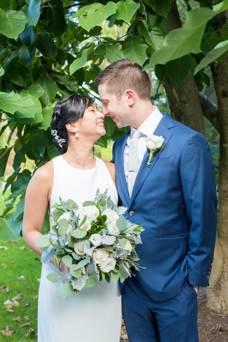 The bride and groom at their Crabtree's Kittle House wedding with an outdoor ceremony and indoor reception in Chappaqua, New York. Photos by Mikkel Paige Photography. This venue in Westchester County is near the Hudson Valley and NYC. She wore an elegant, form-fitting white gown with open back. He wore a blue suit, gray tie and rose boutonniere. #mikkelpaige #hudsonvalleyweddings #crabtreeskittlehouse #fallwedding #westchestervenues #bridestyle #elegantbride #groomstyle #filipinobride