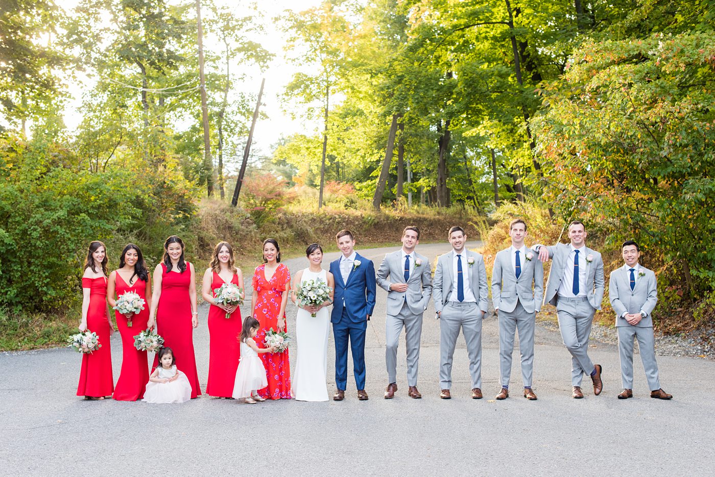 Crabtree's Kittle House wedding with an outdoor ceremony in Chappaqua, New York. Photos by Mikkel Paige Photography. This venue in Westchester County is near the Hudson Valley and NYC. The bride wore a simple form-fitted white gown with open back and bridesmaids wore red in Asian tradition. The groom wore a blue suit and groomsmen gray. #mikkelpaige #hudsonvalleyweddings #crabtreeskittlehouse #fallwedding #westchestervenues #redbridesmaids #filipinowedding #bridestyle #groomstyle #bluesuit