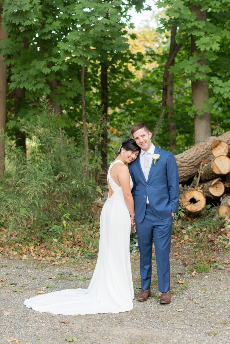 The bride and groom at their Crabtree's Kittle House wedding with an outdoor ceremony and indoor reception in Chappaqua, New York. Photos by Mikkel Paige Photography. This venue in Westchester County is near the Hudson Valley and NYC. She wore an elegant, form-fitting white gown with open back. He wore a blue suit, gray tie and rose boutonniere. #mikkelpaige #hudsonvalleyweddings #crabtreeskittlehouse #fallwedding #westchestervenues #bridestyle #elegantbride #groomstyle #filipinobride