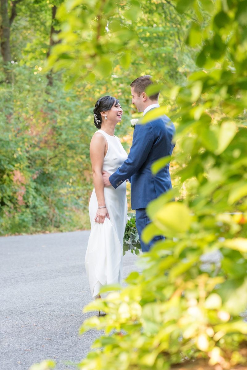 The bride and groom at their Crabtree's Kittle House wedding with an outdoor ceremony and indoor reception in Chappaqua, New York. Photos by Mikkel Paige Photography. This venue in Westchester County is near the Hudson Valley and NYC. She wore an elegant, form-fitting white gown with open back. He wore a blue suit, gray tie and rose boutonniere. #mikkelpaige #hudsonvalleyweddings #crabtreeskittlehouse #fallwedding #westchestervenues #bridestyle #elegantbride #groomstyle #filipinobride