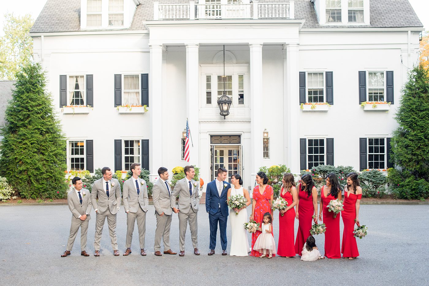 Crabtree's Kittle House wedding with an outdoor ceremony in Chappaqua, New York. Photos by Mikkel Paige Photography. This venue in Westchester County is near the Hudson Valley and NYC. The bride wore a simple form-fitted white gown with open back and bridesmaids wore red in Asian tradition. The groom wore a blue suit and groomsmen gray. #mikkelpaige #hudsonvalleyweddings #crabtreeskittlehouse #fallwedding #westchestervenues #redbridesmaids #filipinowedding #bridestyle #groomstyle #bluesuit