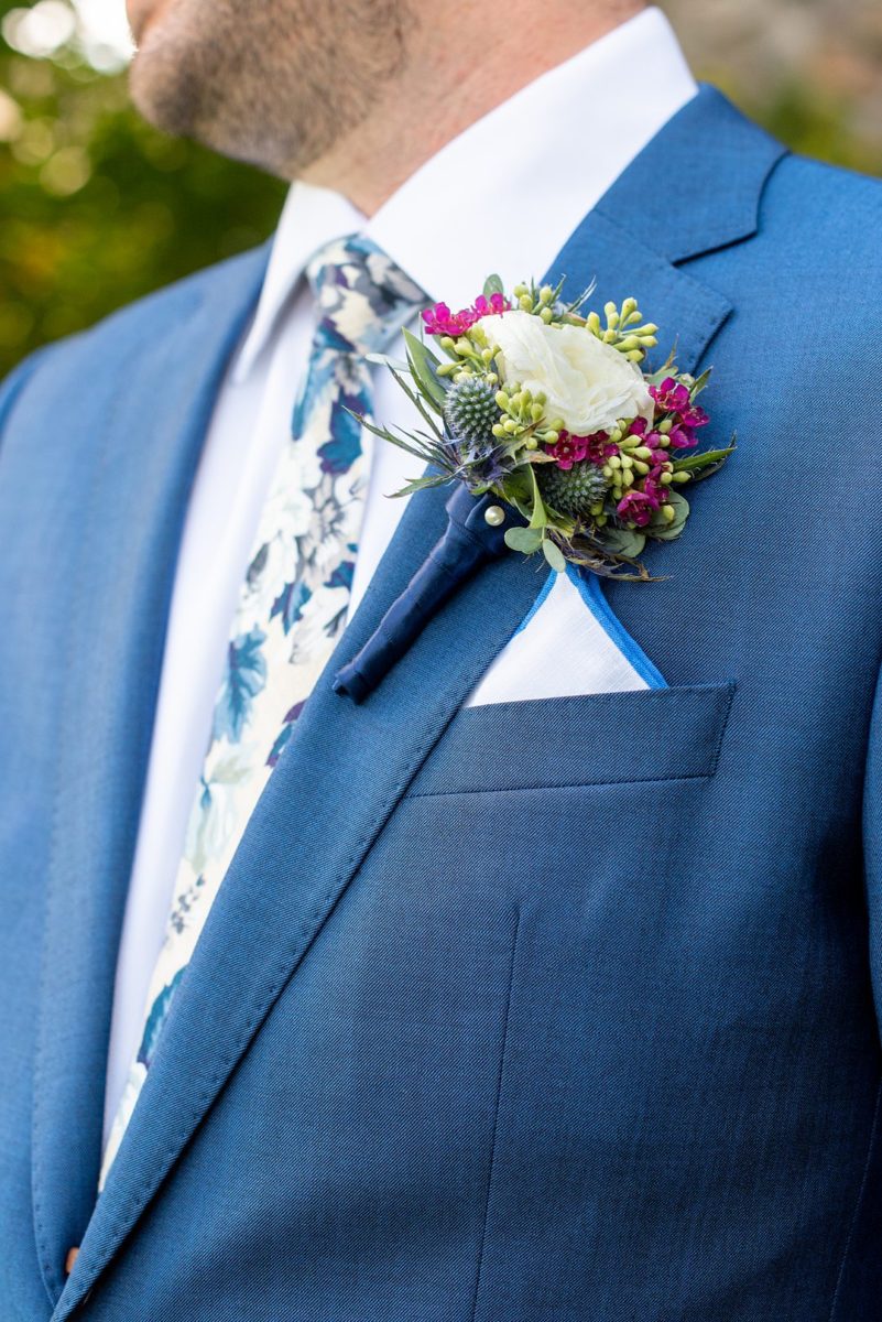Photos at New Jersey wedding venue, Crystal Springs Resort, in Hamburg with an outdoor ceremony option and indoor reception, by Mikkel Paige Photography. The groom wore a colorful blue suit, floral tie and boutonniere with a white spray rose, green eucalyptus and small pink flowers, tied with a navy ribbon. #mikkelpaige #CrystalSprings #NJweddingvenues #NewJerseyWedding #NJweddingphotographer #boutonniere #groomstyle #fallwedding #floraltie